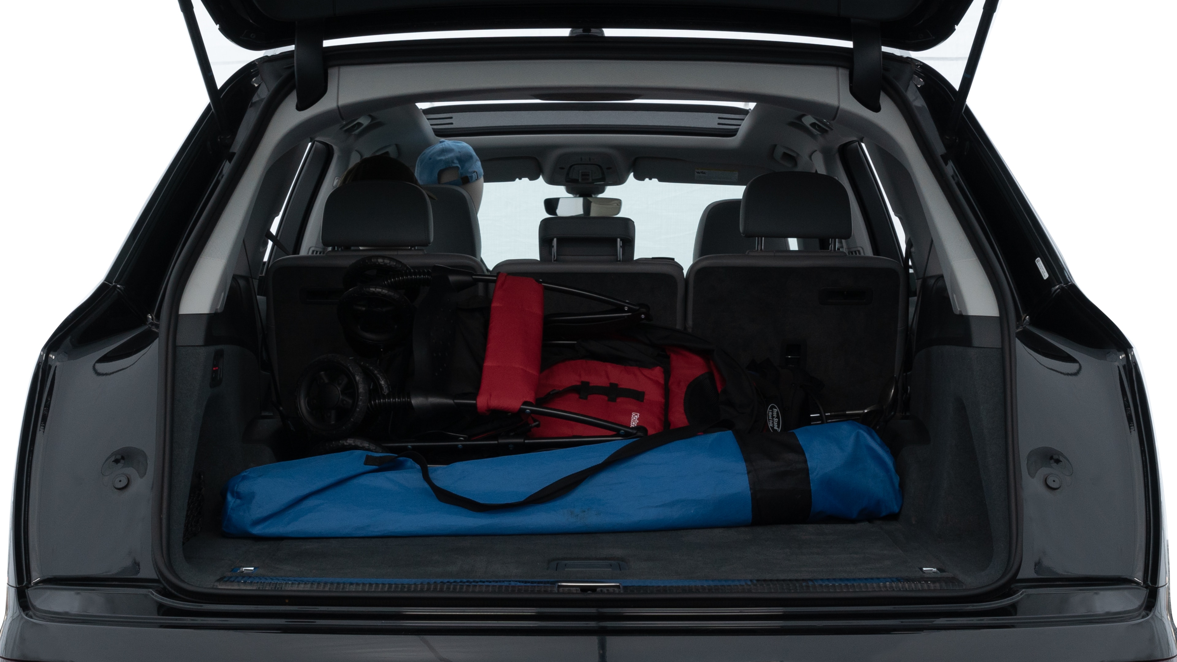 The trunk lid is open showing full view of the trunk. A baby stroller, three grocery carriers, two camping chairs in the carrying bag, and a set of golf clubs are placed inside.