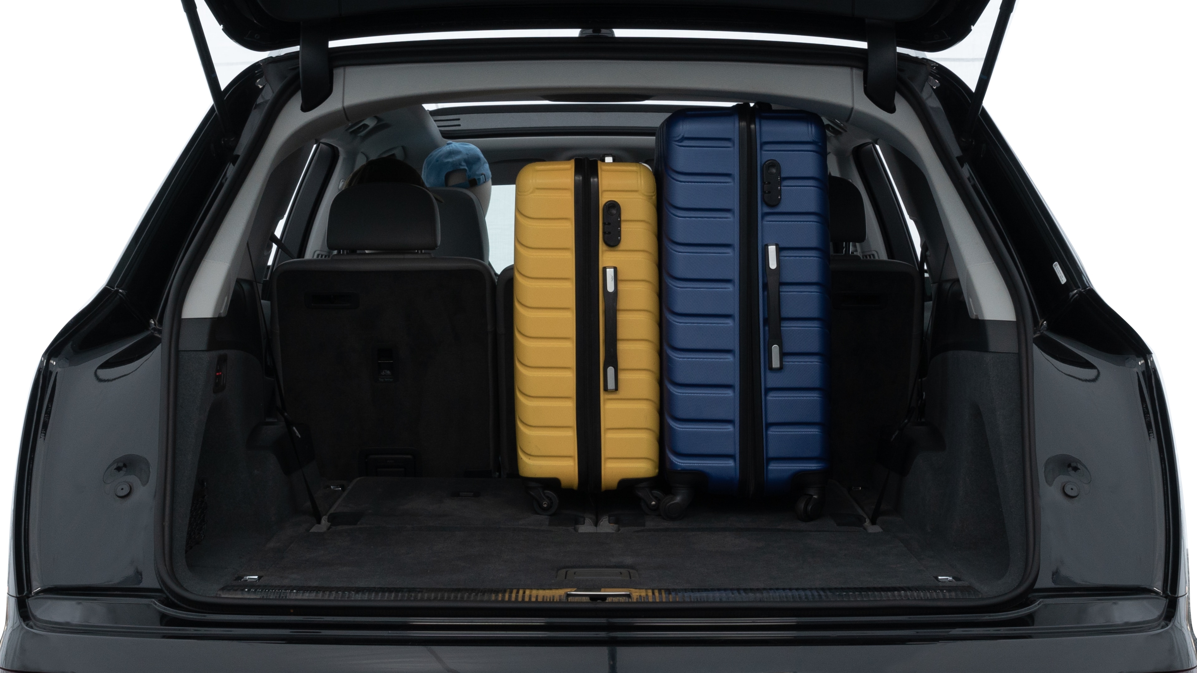 The trunk lid is open, showing full view of the trunk space. One large, two medium, and two small suitcases are placed inside.