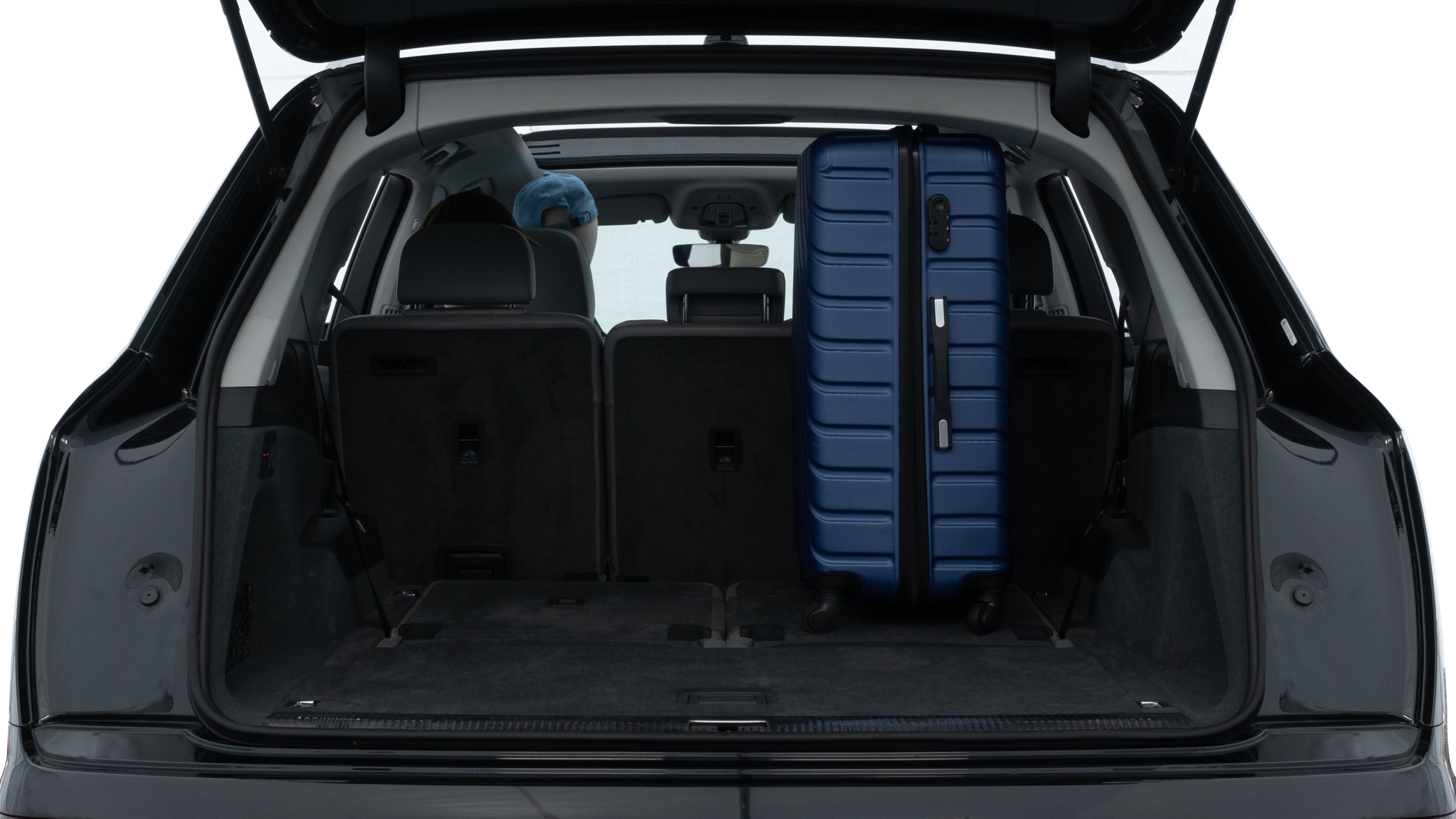 The trunk lid is open, showing full view of the trunk space. One large, two medium, and two small suitcases are placed inside.