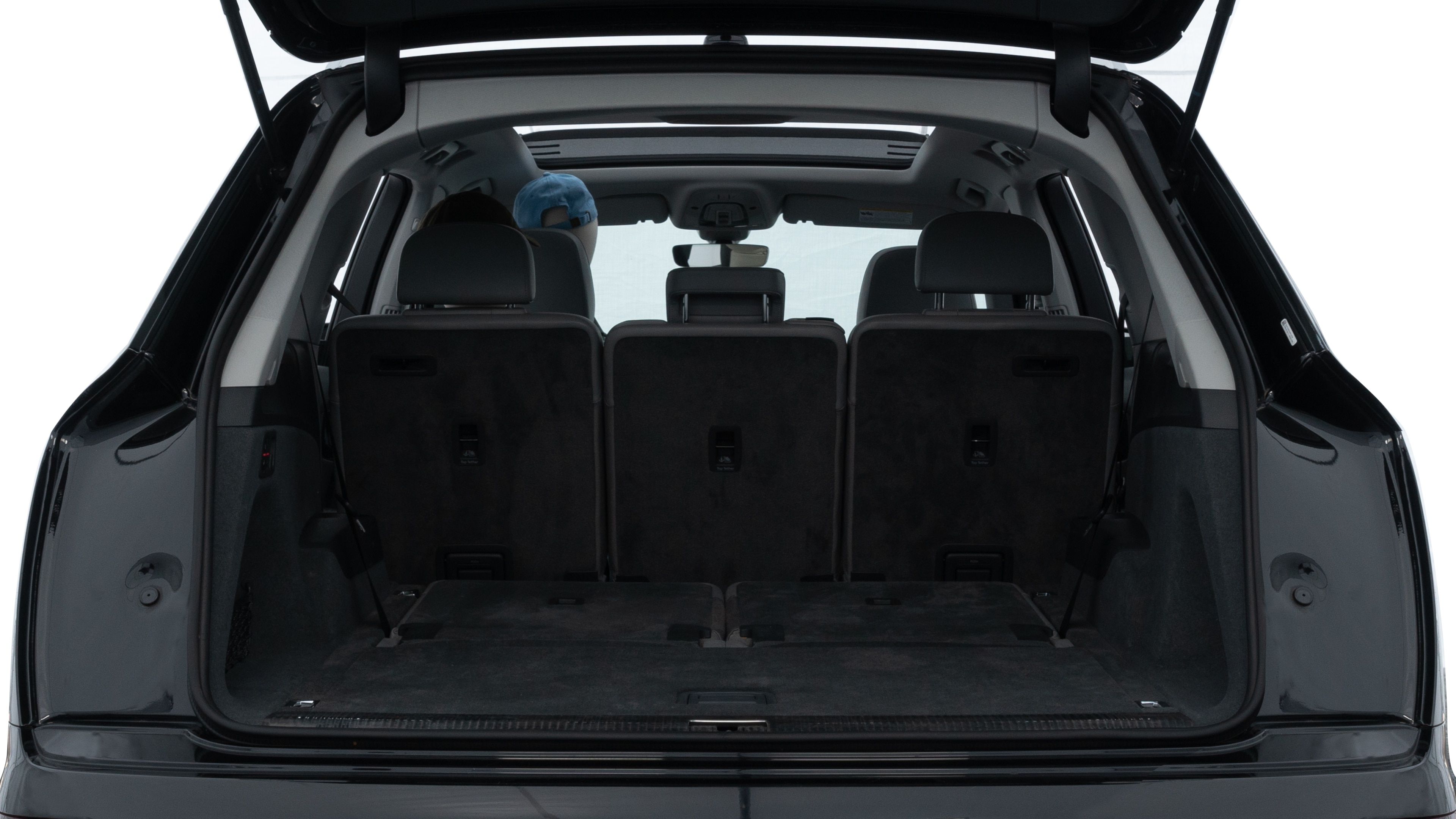 The trunk lid is open, showing full view of the trunk space. One large, two medium, and two small suitcases are placed inside.