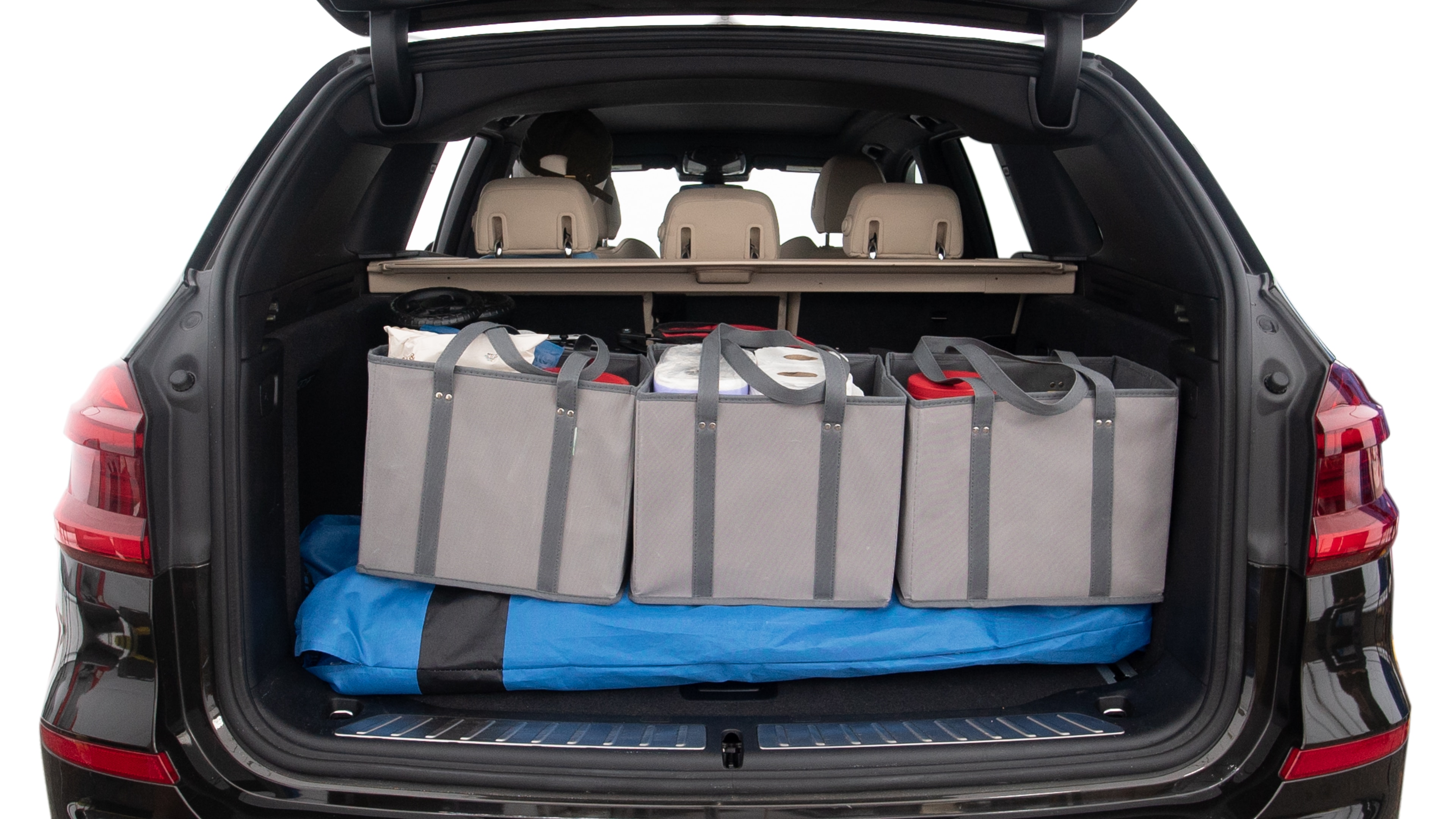The trunk lid is open showing full view of the trunk. A baby stroller, three grocery carriers, two camping chairs in the carrying bag, and a set of golf clubs are placed inside.