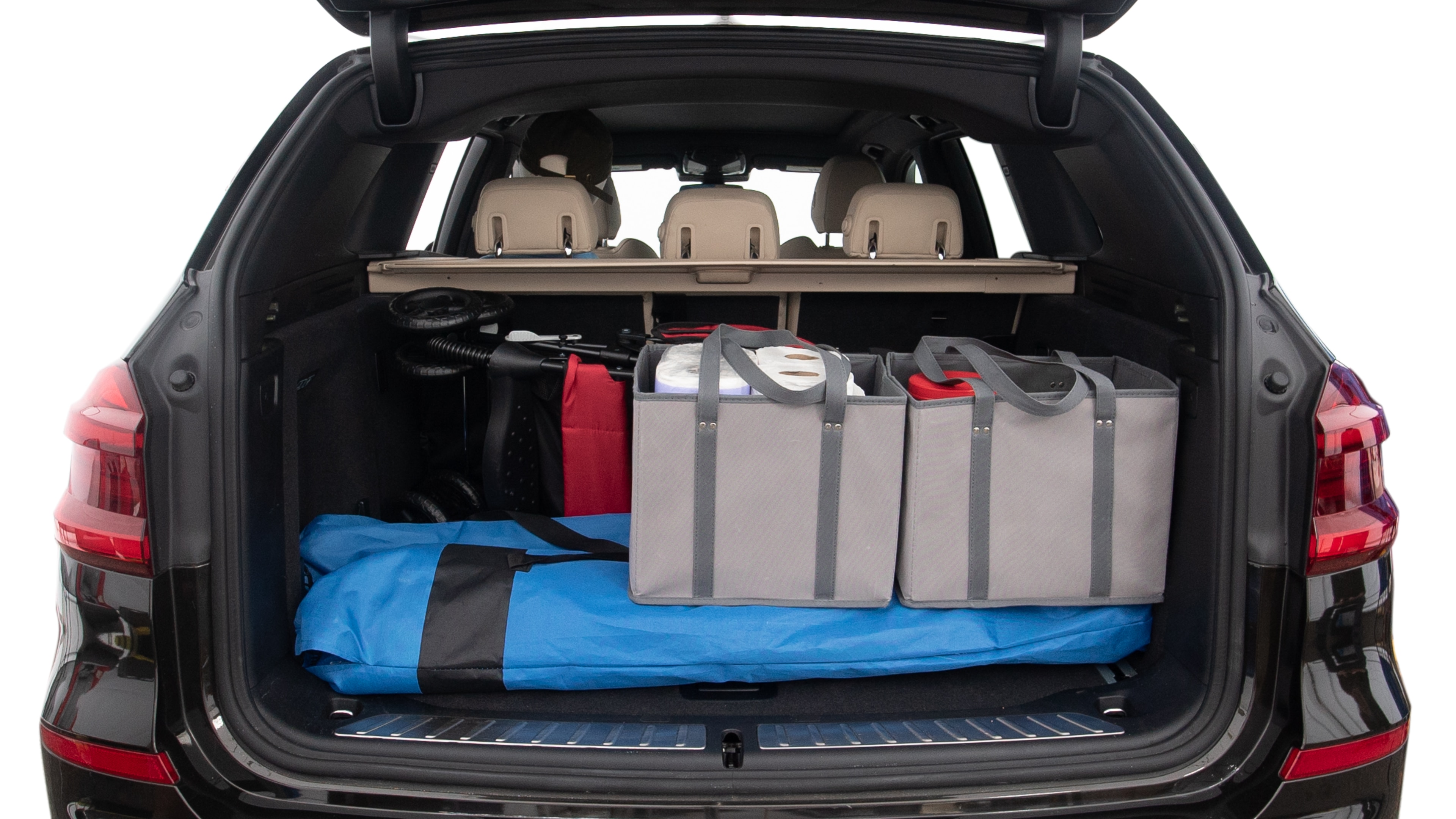 The trunk lid is open showing full view of the trunk. A baby stroller, three grocery carriers, two camping chairs in the carrying bag, and a set of golf clubs are placed inside.