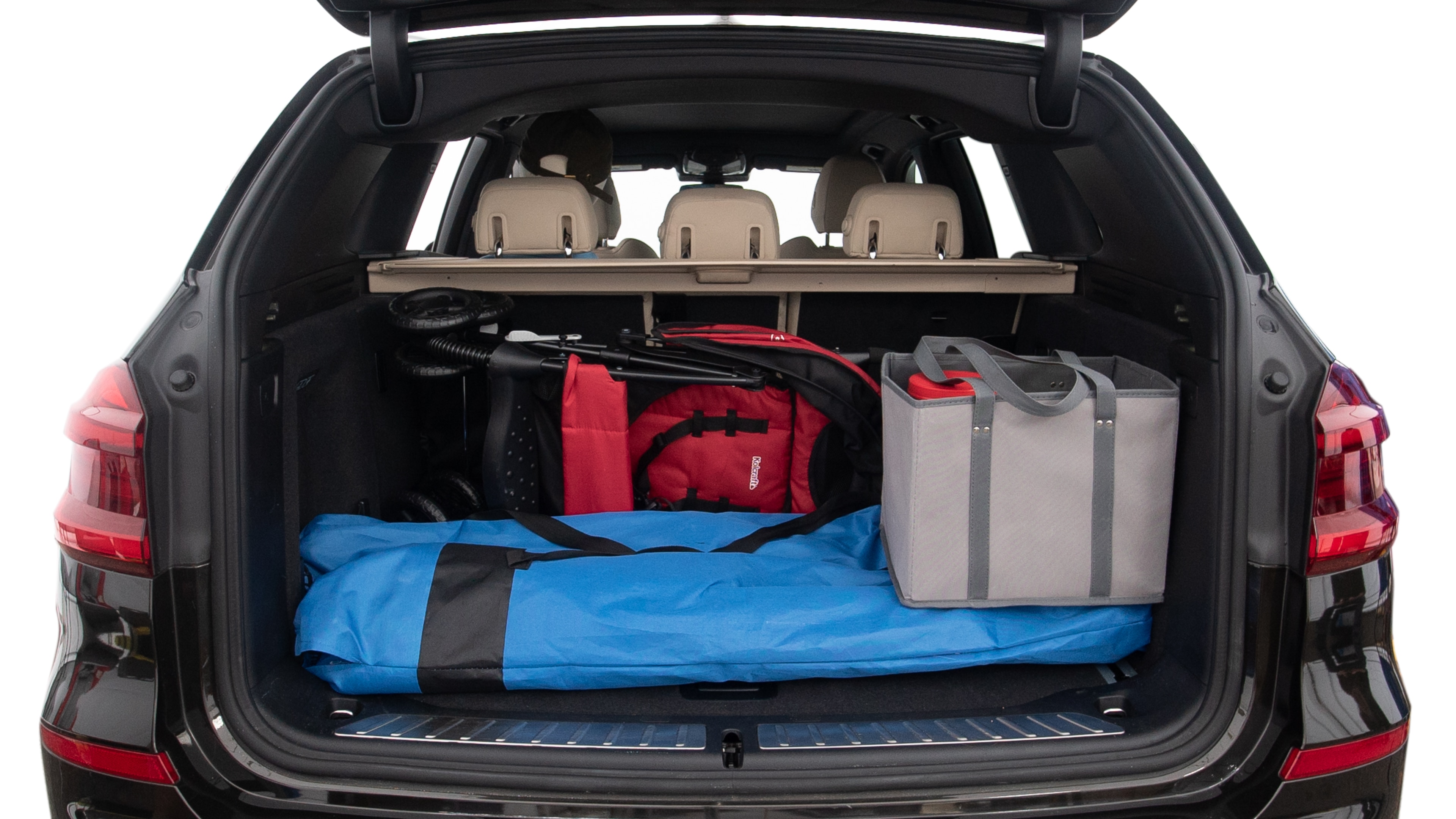 The trunk lid is open showing full view of the trunk. A baby stroller, three grocery carriers, two camping chairs in the carrying bag, and a set of golf clubs are placed inside.