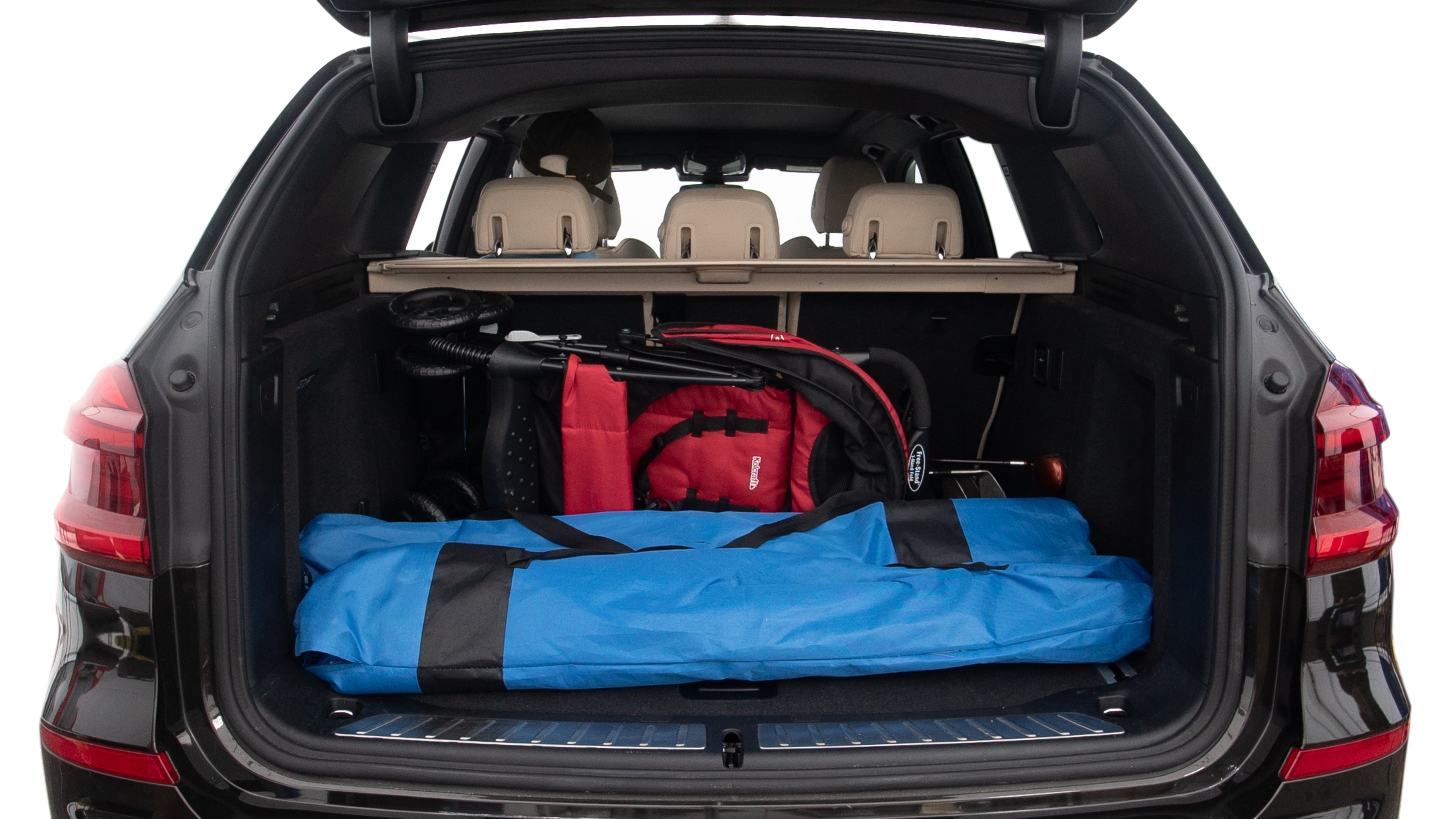 The trunk lid is open showing full view of the trunk. A baby stroller, three grocery carriers, two camping chairs in the carrying bag, and a set of golf clubs are placed inside.