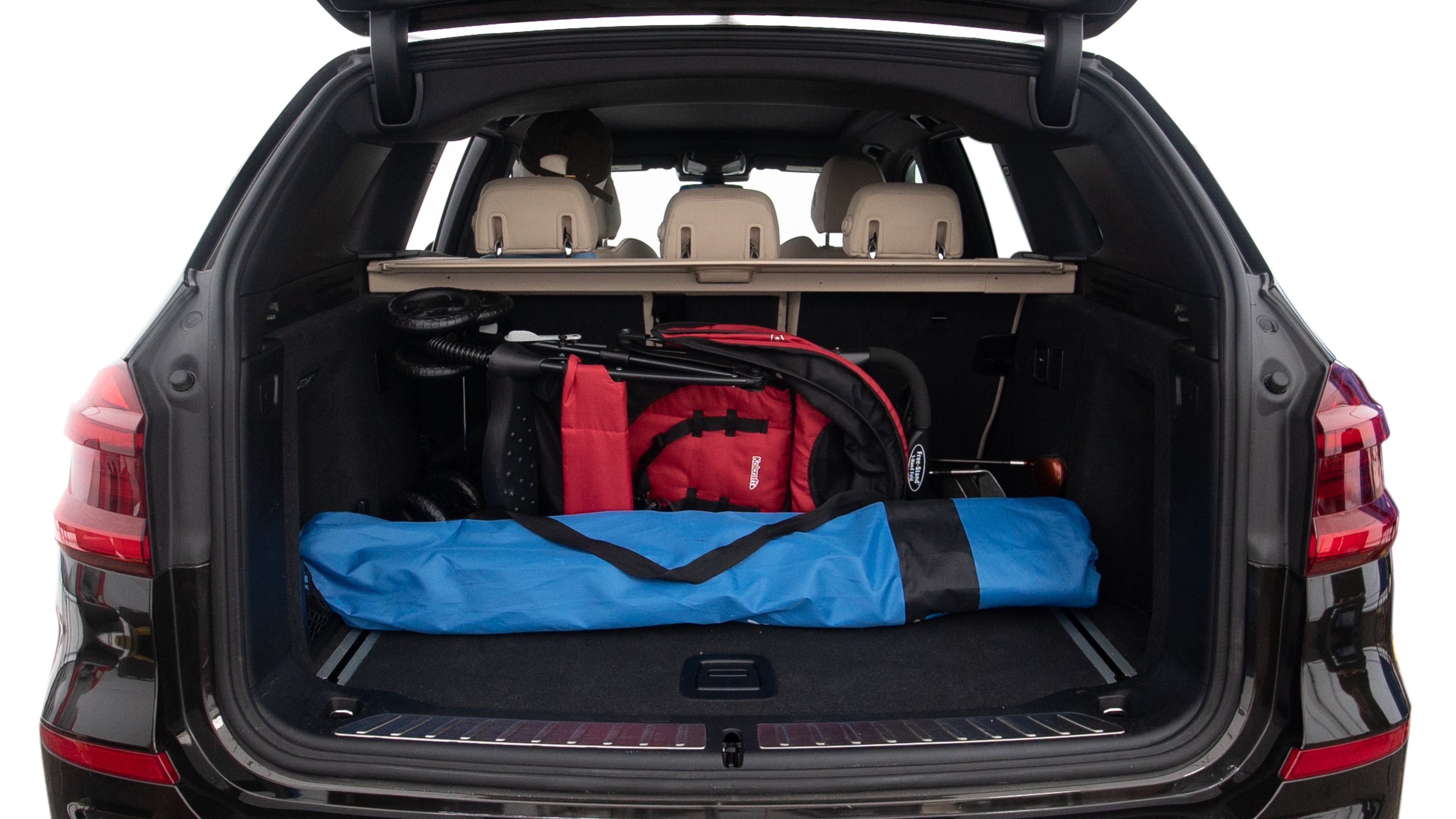 The trunk lid is open showing full view of the trunk. A baby stroller, three grocery carriers, two camping chairs in the carrying bag, and a set of golf clubs are placed inside.
