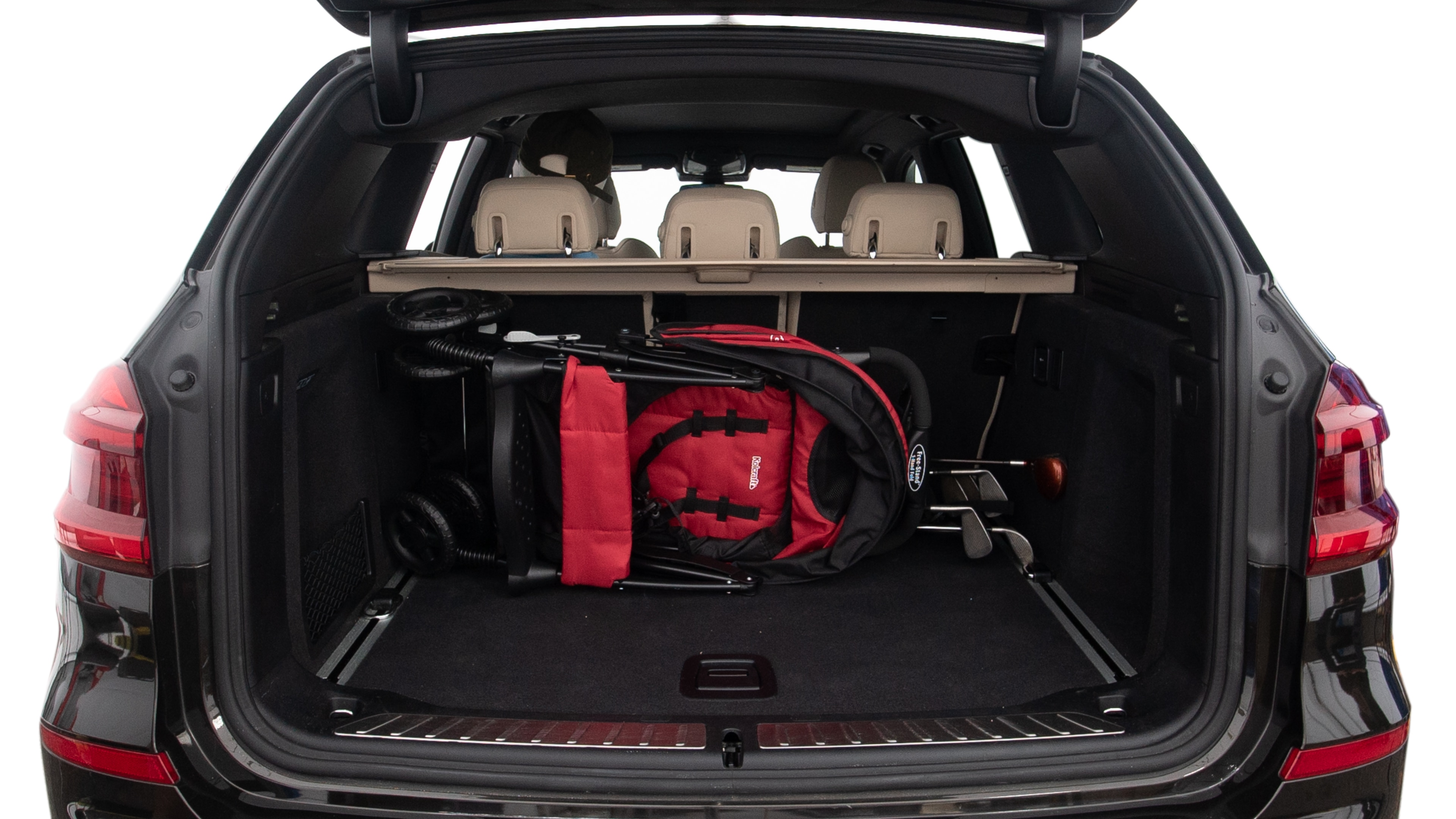 The trunk lid is open showing full view of the trunk. A baby stroller, three grocery carriers, two camping chairs in the carrying bag, and a set of golf clubs are placed inside.