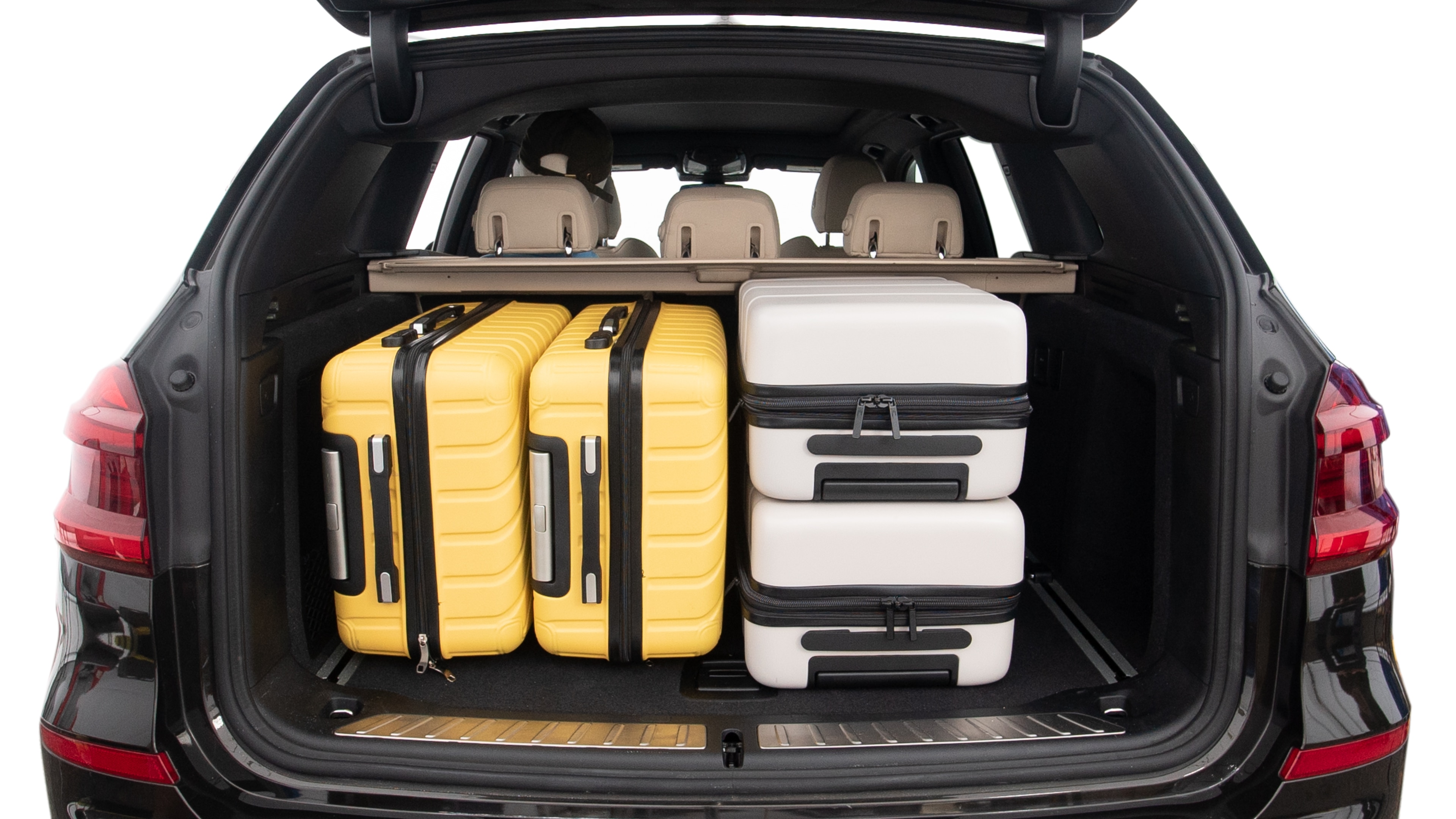The trunk lid is open, showing full view of the trunk space. Two large and two small suitcases are placed inside.