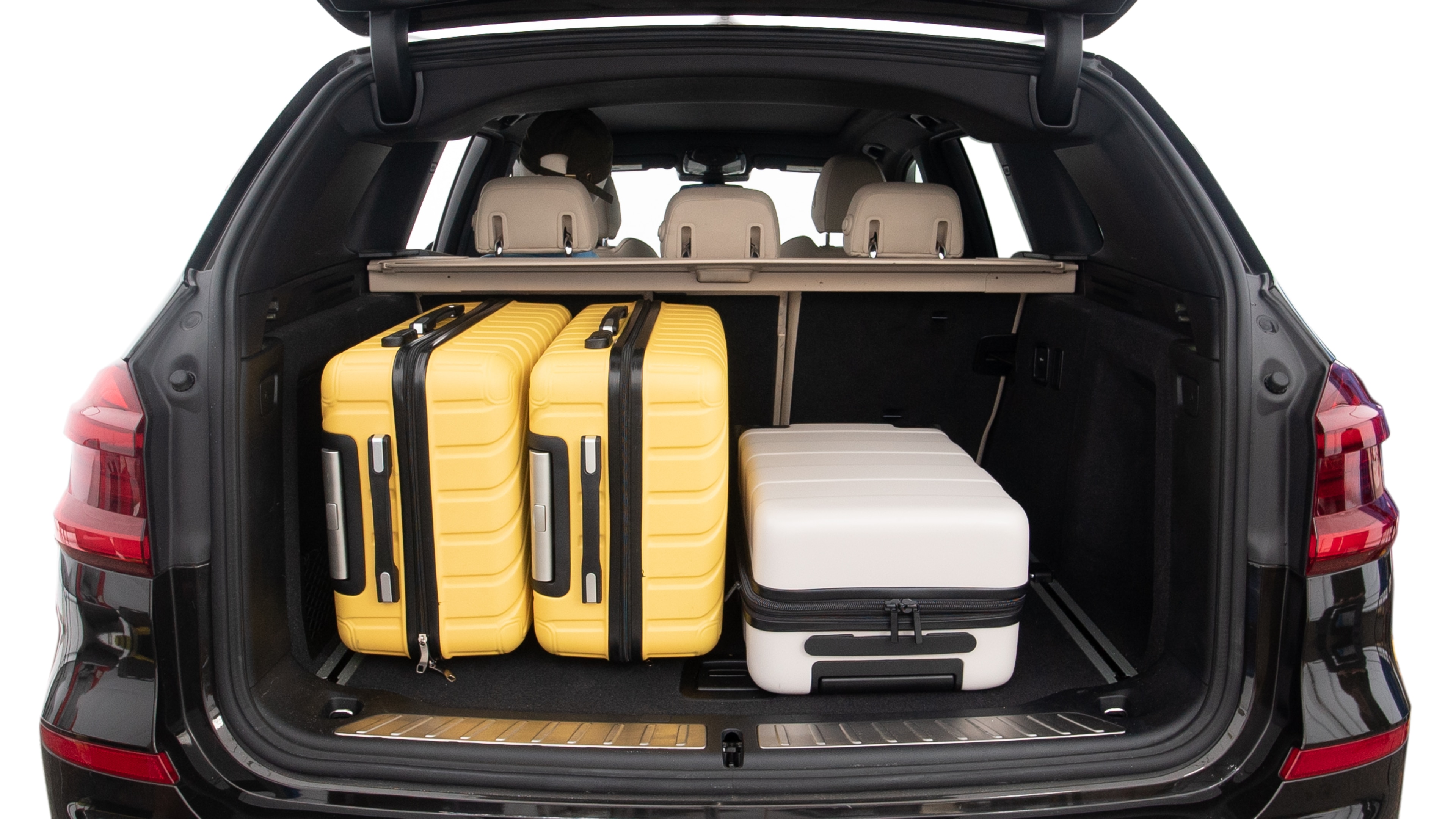 The trunk lid is open, showing full view of the trunk space. Two large and two small suitcases are placed inside.