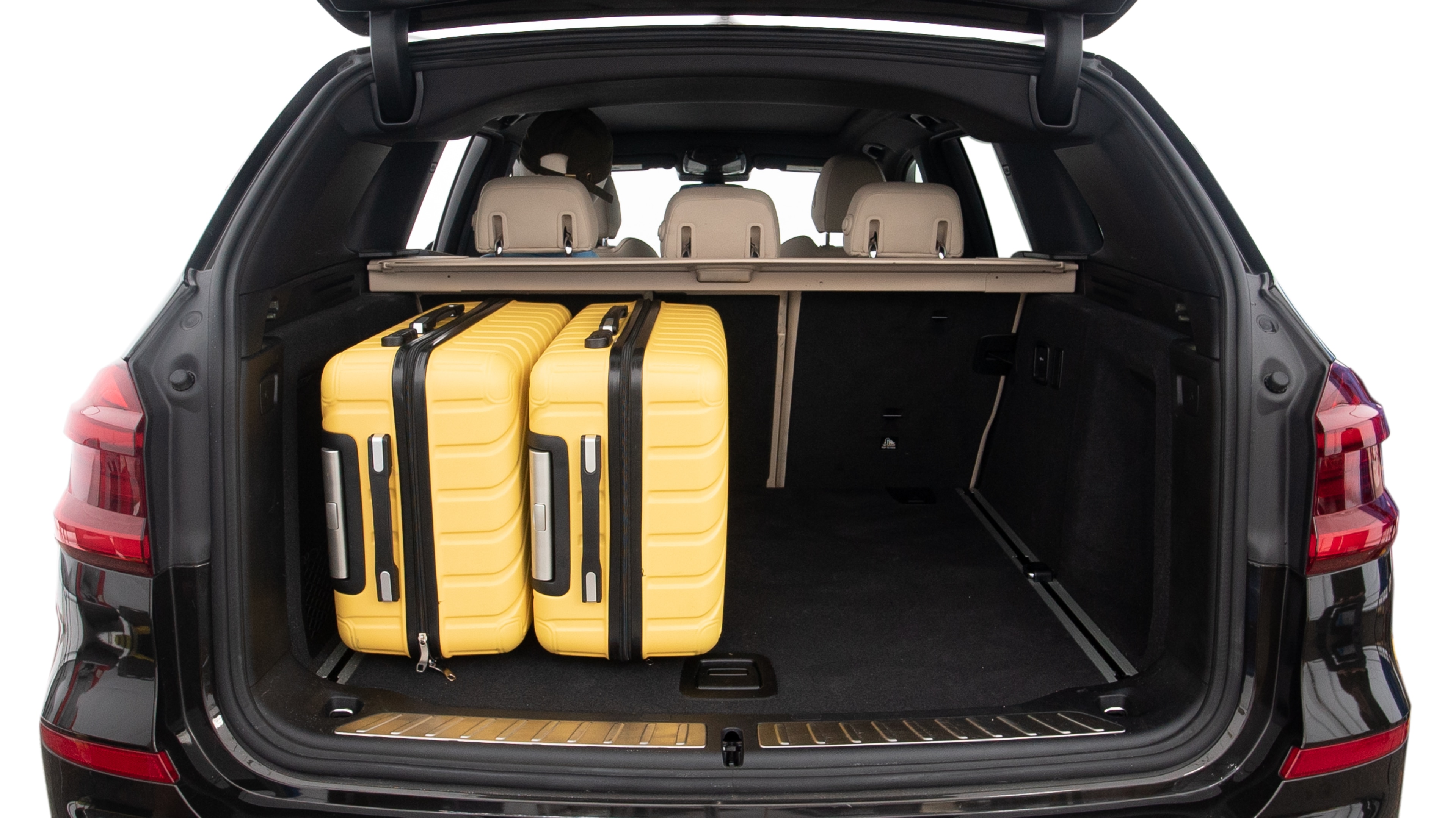 The trunk lid is open, showing full view of the trunk space. Two large and two small suitcases are placed inside.