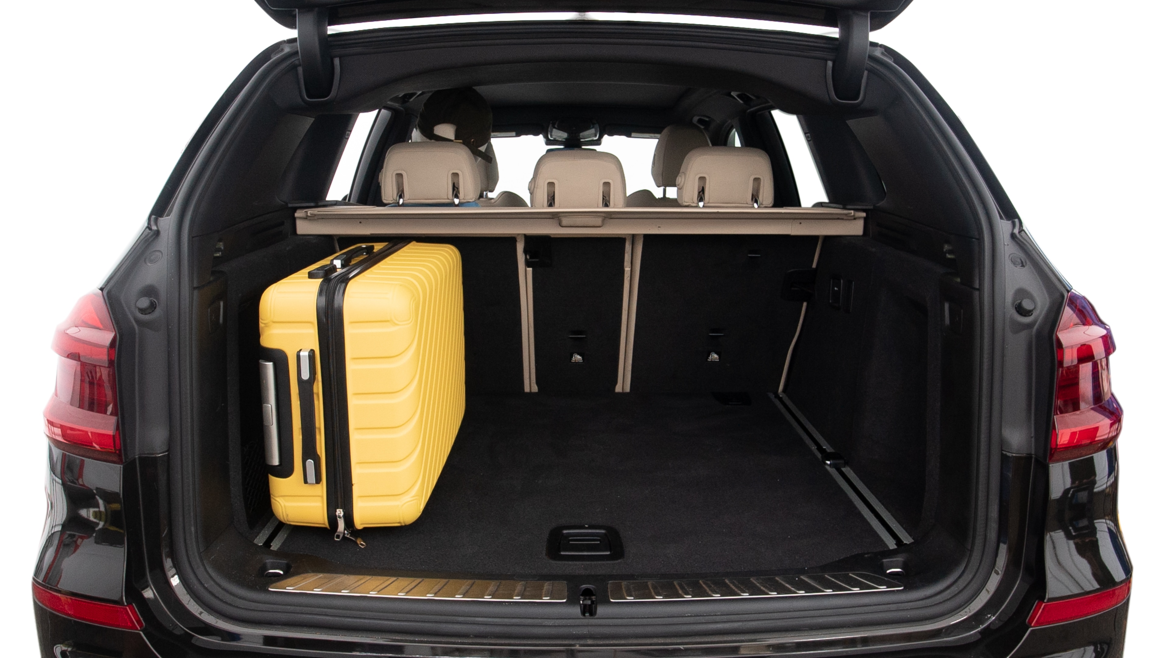 The trunk lid is open, showing full view of the trunk space. Two large and two small suitcases are placed inside.