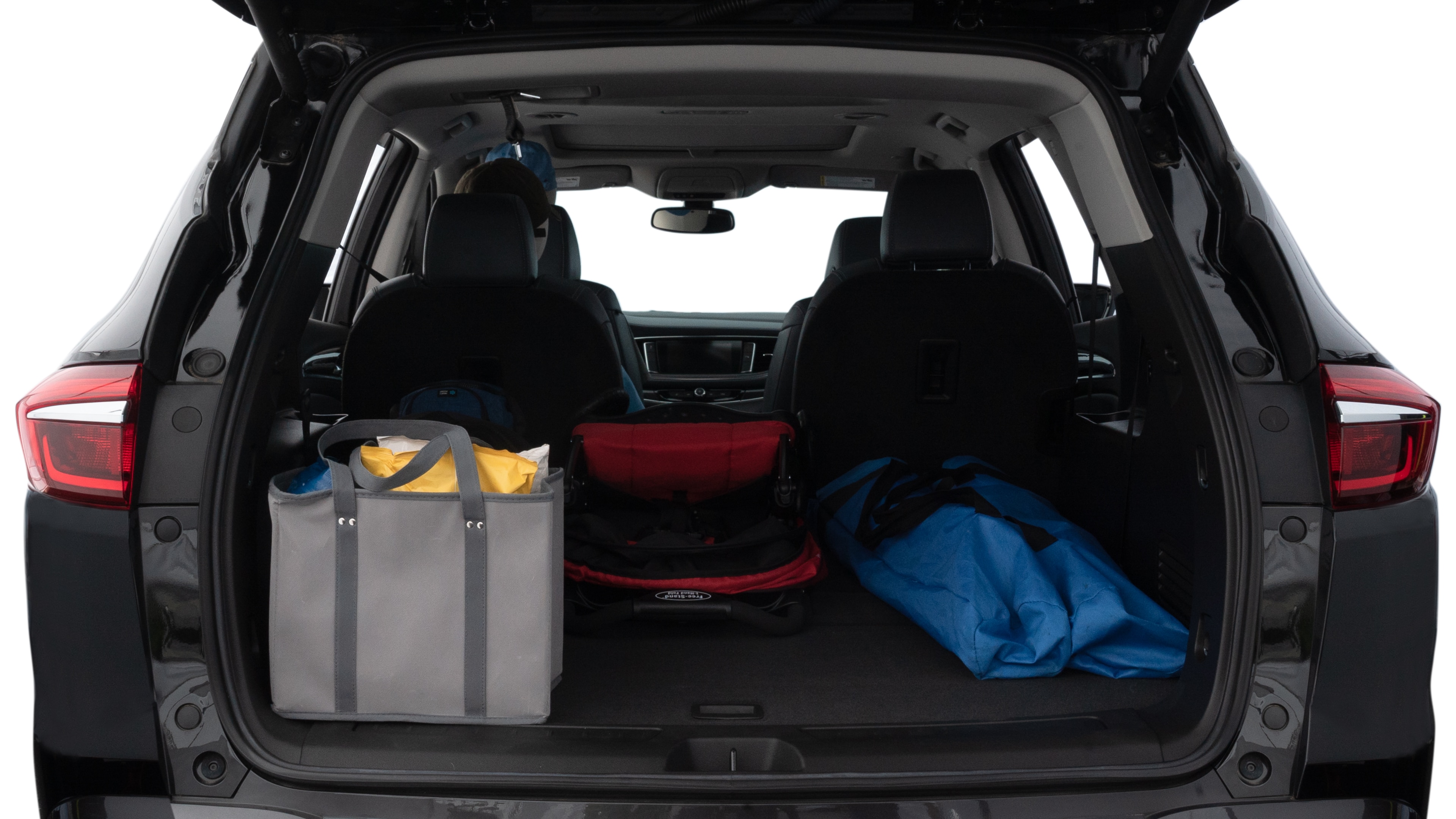 The trunk lid is open showing full view of the trunk. A baby stroller, three grocery carriers, two camping chairs in the carrying bag, and a set of golf clubs are placed inside.