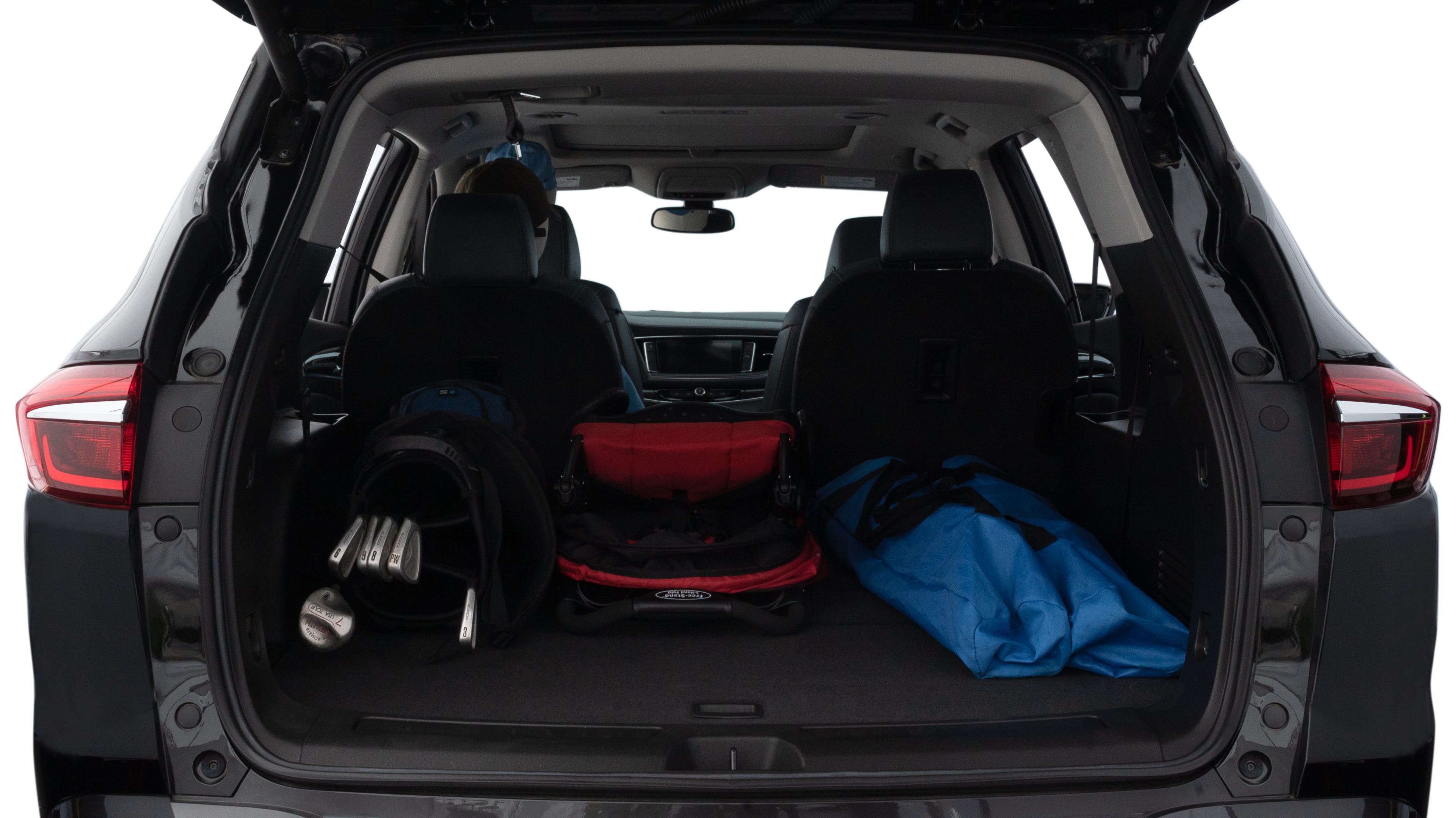 The trunk lid is open showing full view of the trunk. A baby stroller, three grocery carriers, two camping chairs in the carrying bag, and a set of golf clubs are placed inside.
