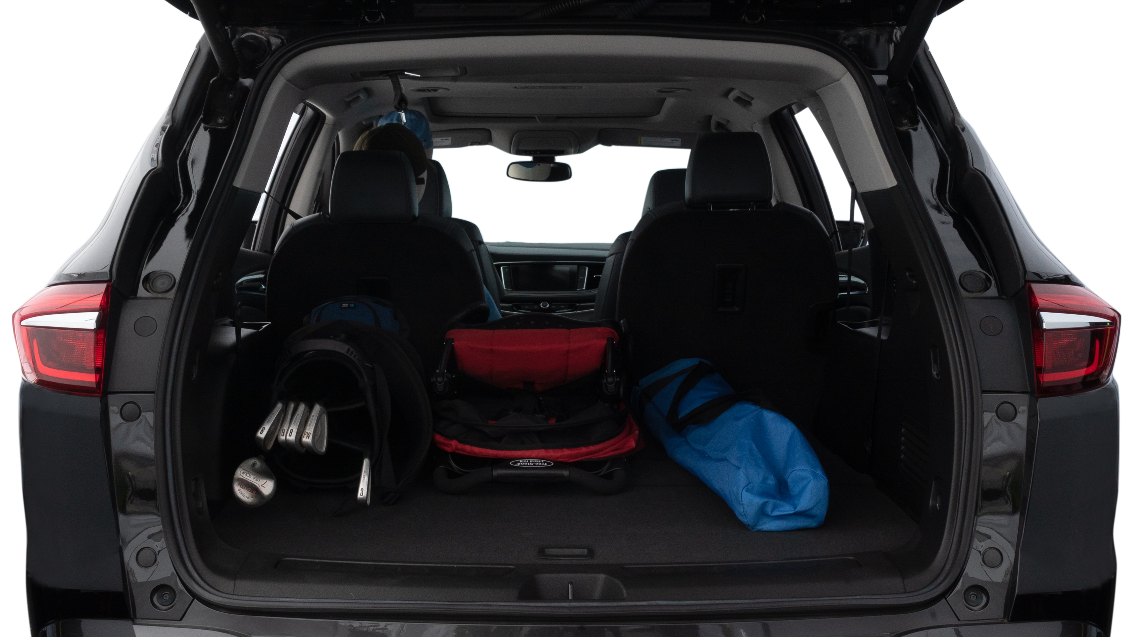 The trunk lid is open showing full view of the trunk. A baby stroller, three grocery carriers, two camping chairs in the carrying bag, and a set of golf clubs are placed inside.