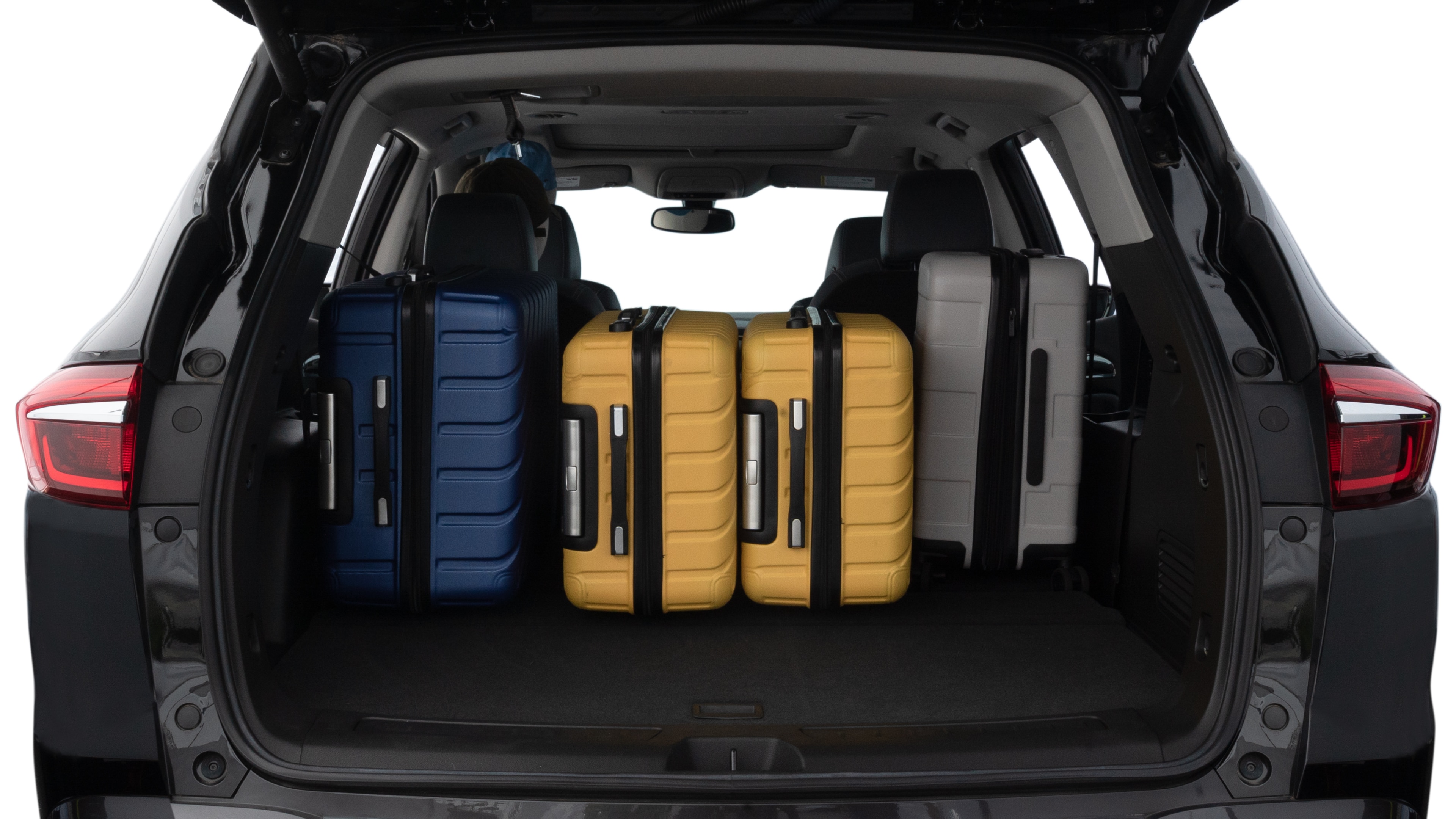 The trunk lid is open, showing full view of the trunk space. One large, two medium, and two small suitcases are placed inside.