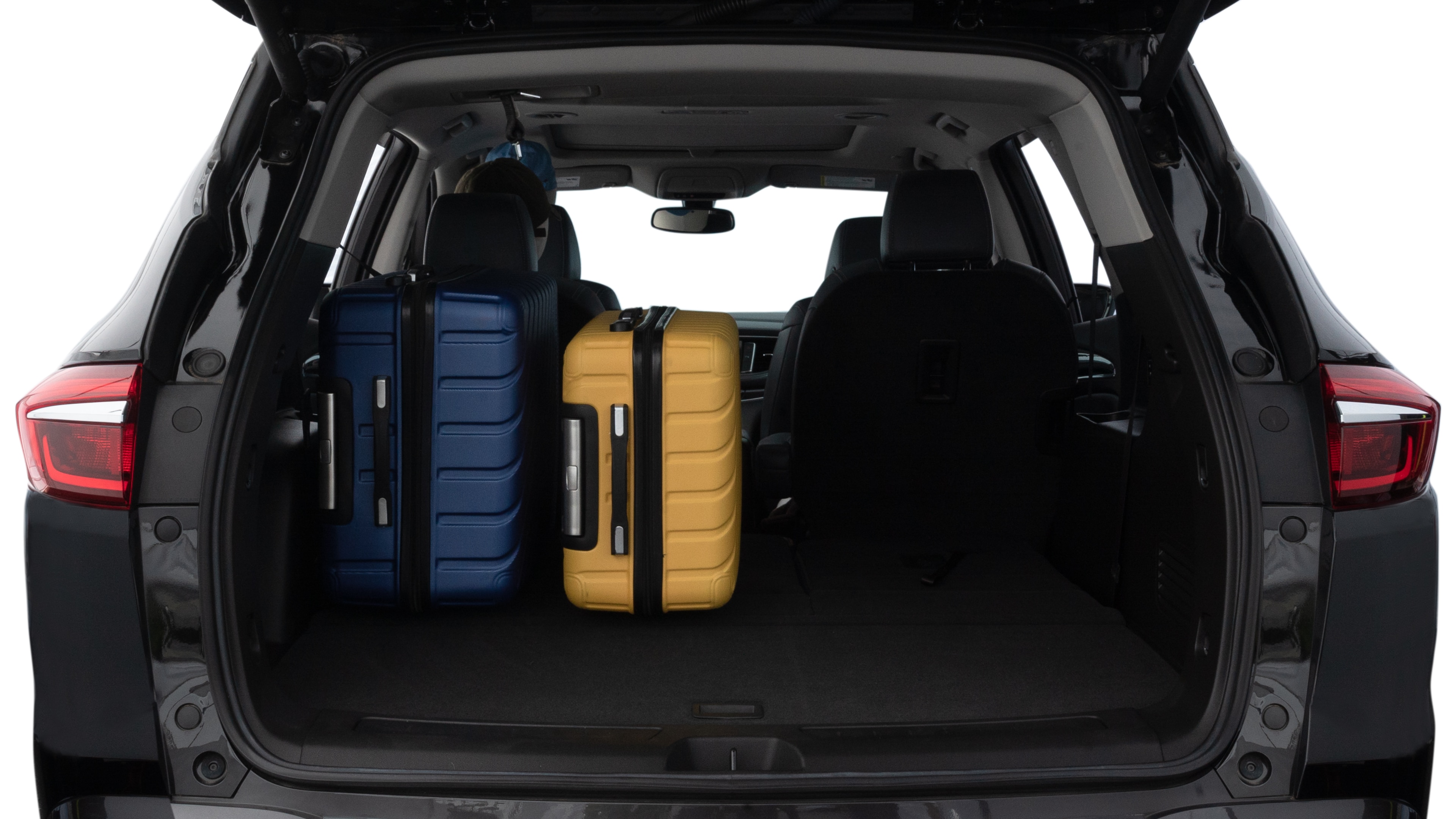 The trunk lid is open, showing full view of the trunk space. One large, two medium, and two small suitcases are placed inside.