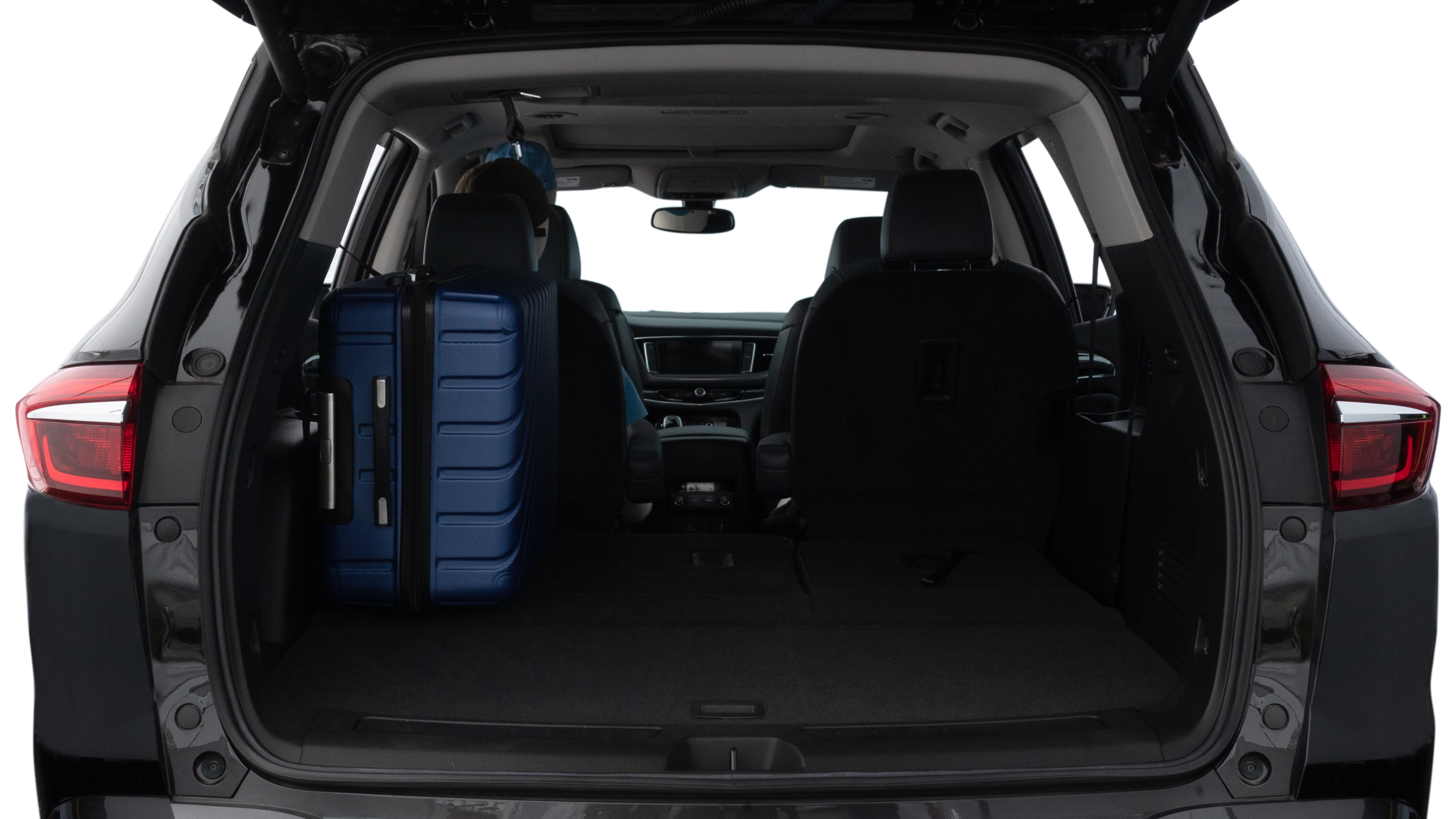 The trunk lid is open, showing full view of the trunk space. One large, two medium, and two small suitcases are placed inside.