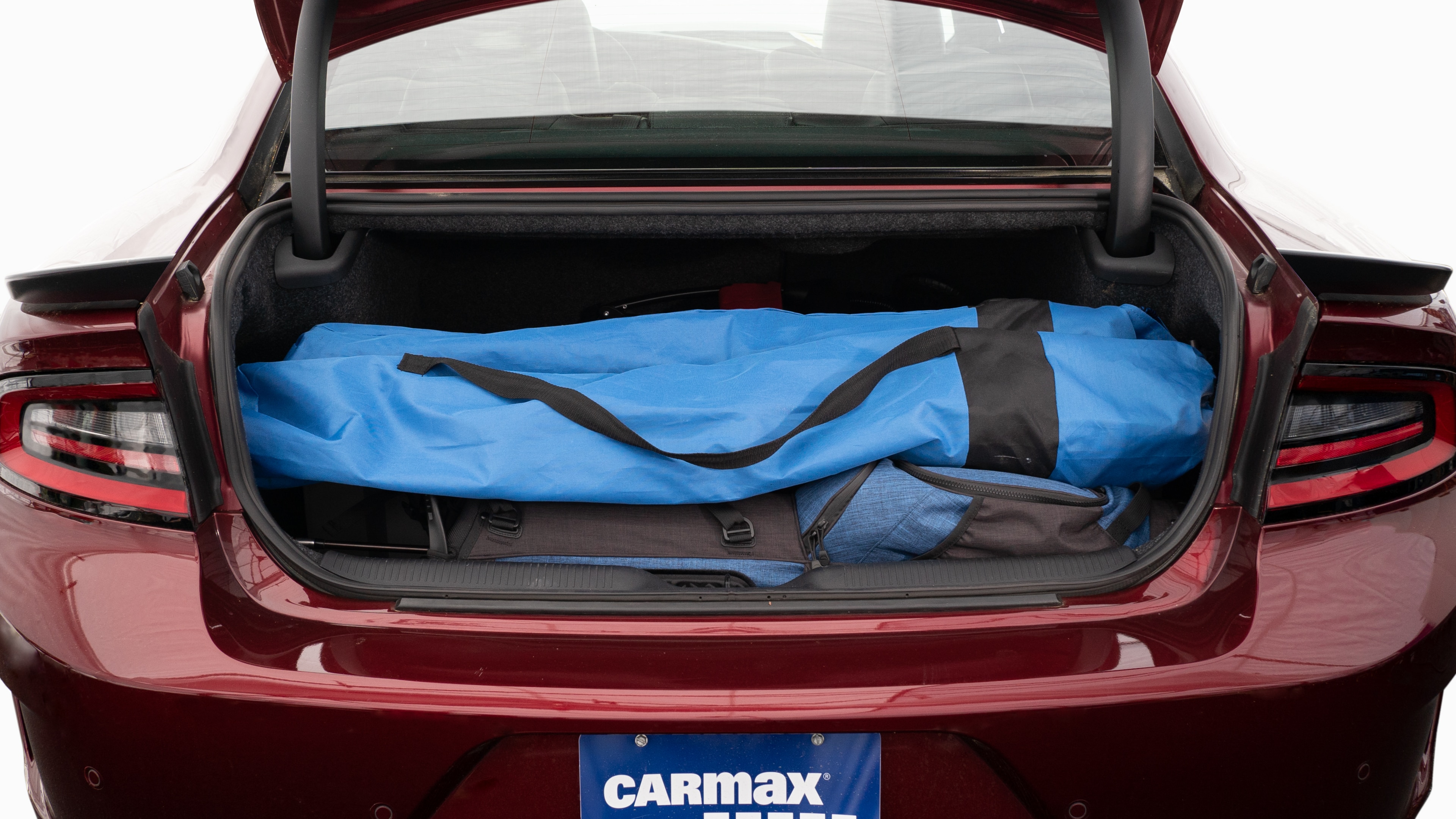 The trunk lid is open showing full view of the trunk. A baby stroller, four grocery carriers, a yoga mat, and a set of golf clubs are placed inside.