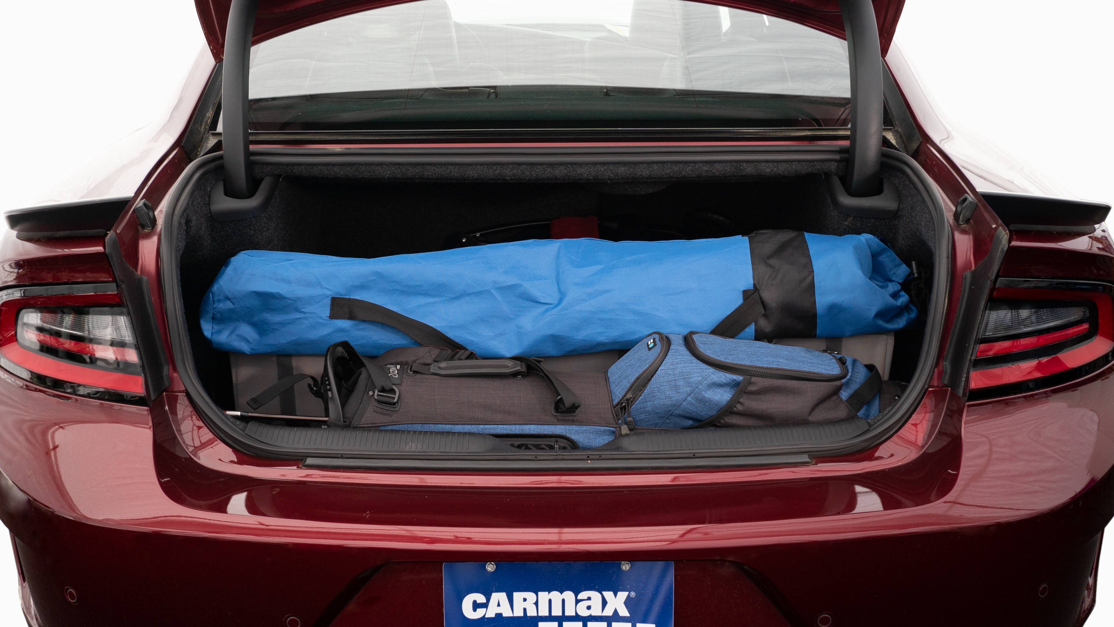The trunk lid is open showing full view of the trunk. A baby stroller, four grocery carriers, a yoga mat, and a set of golf clubs are placed inside.