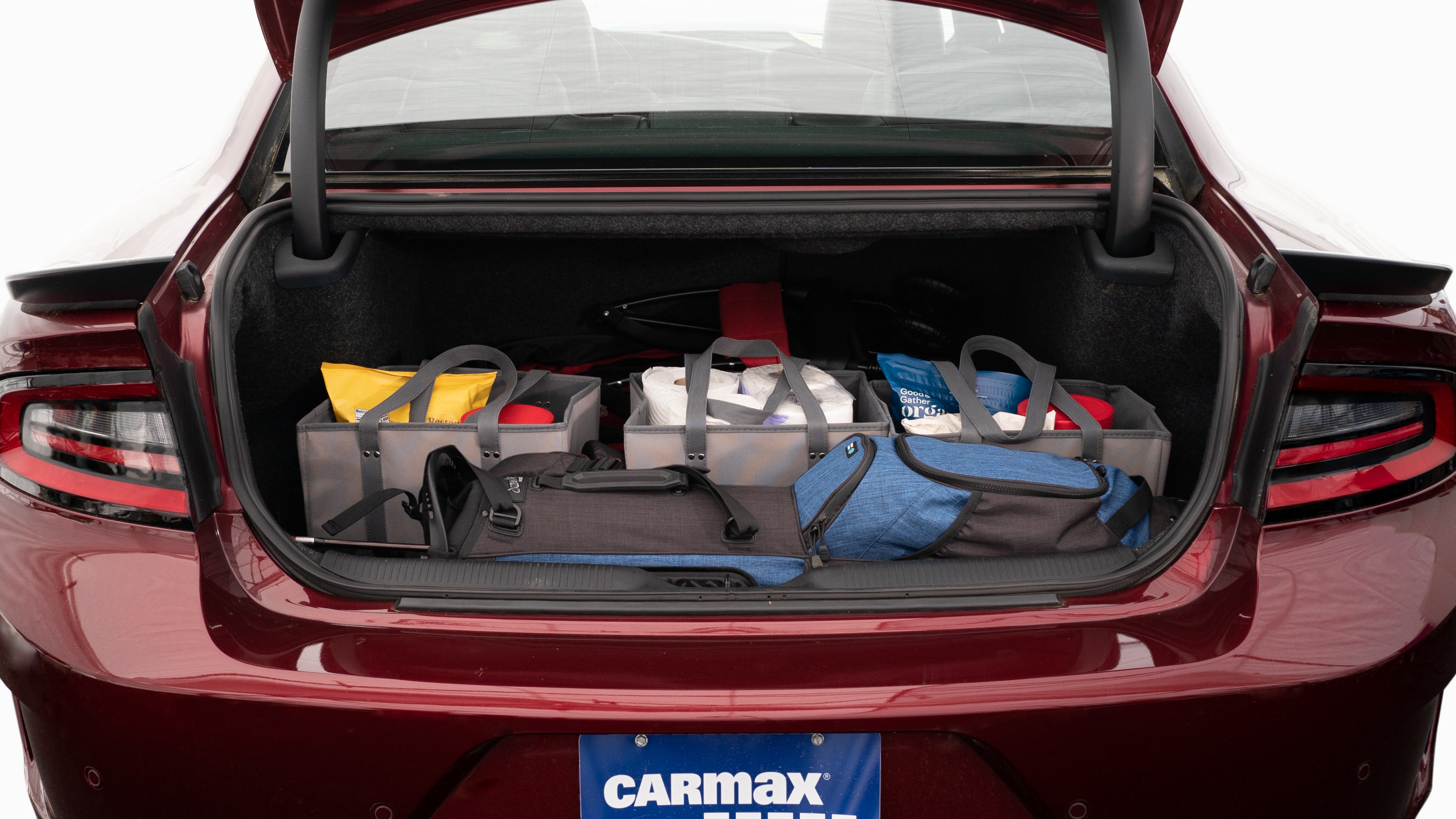The trunk lid is open showing full view of the trunk. A baby stroller, four grocery carriers, a yoga mat, and a set of golf clubs are placed inside.