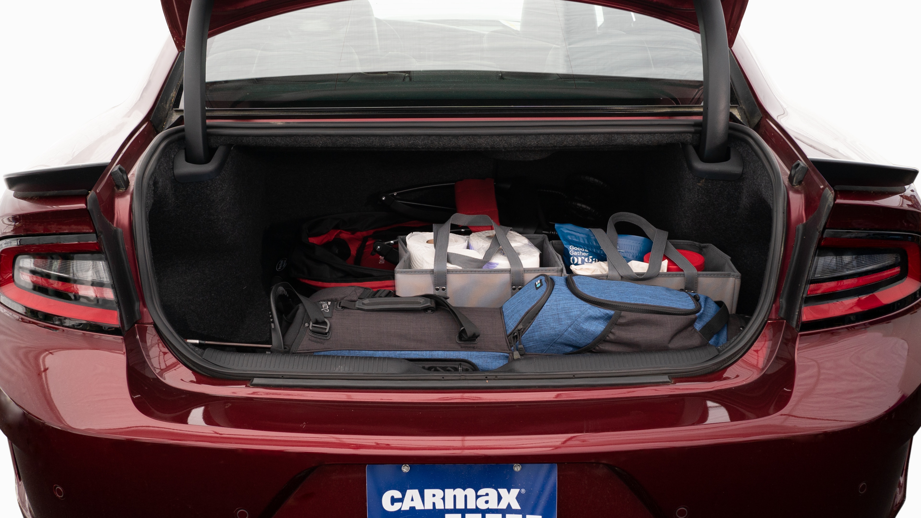 The trunk lid is open showing full view of the trunk. A baby stroller, four grocery carriers, a yoga mat, and a set of golf clubs are placed inside.
