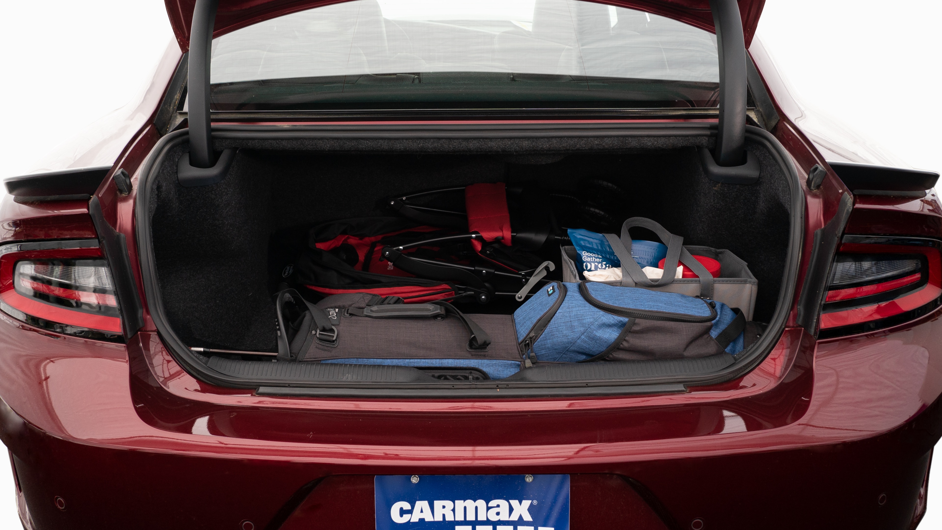 The trunk lid is open showing full view of the trunk. A baby stroller, four grocery carriers, a yoga mat, and a set of golf clubs are placed inside.