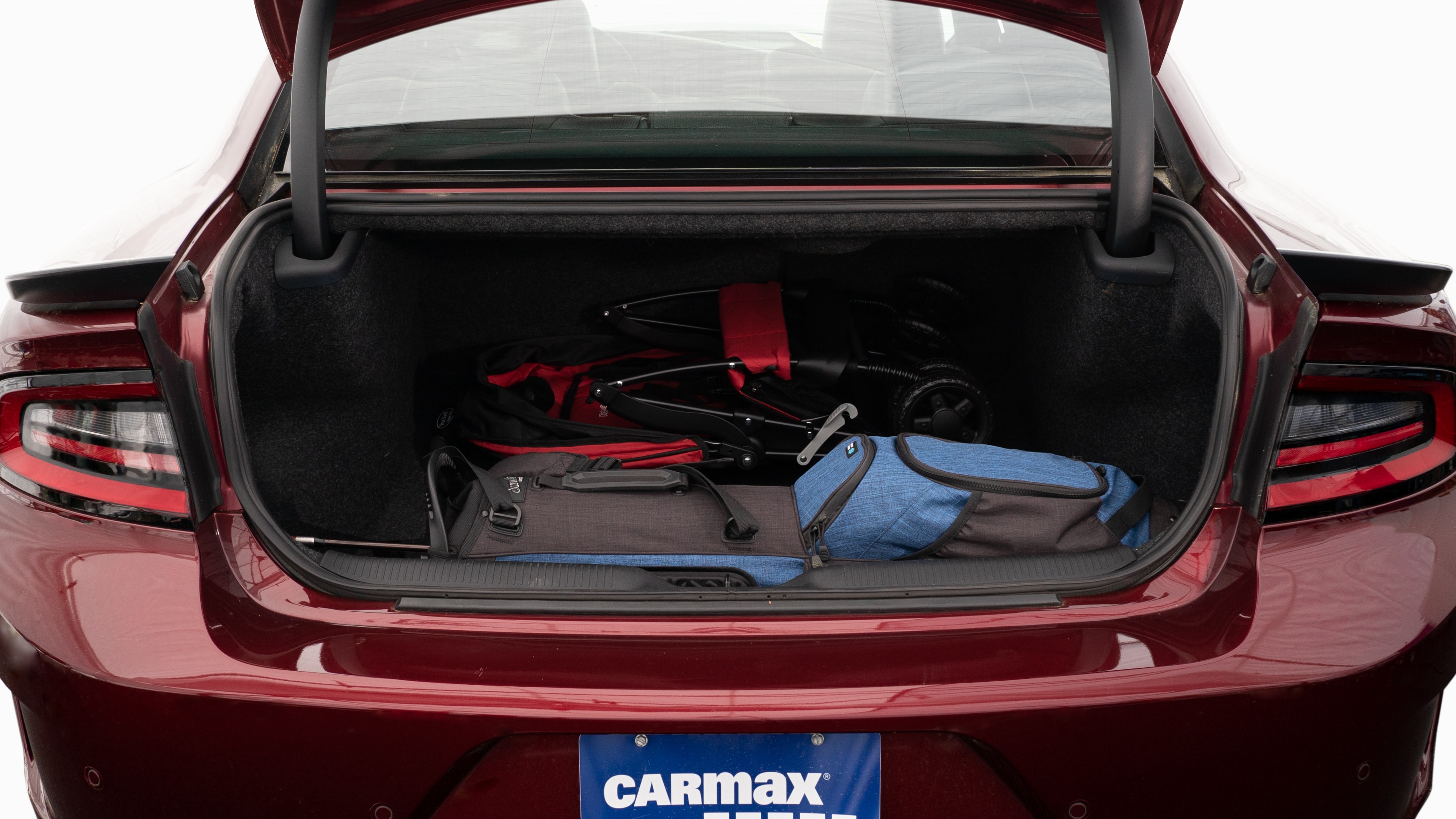 The trunk lid is open showing full view of the trunk. A baby stroller, four grocery carriers, a yoga mat, and a set of golf clubs are placed inside.
