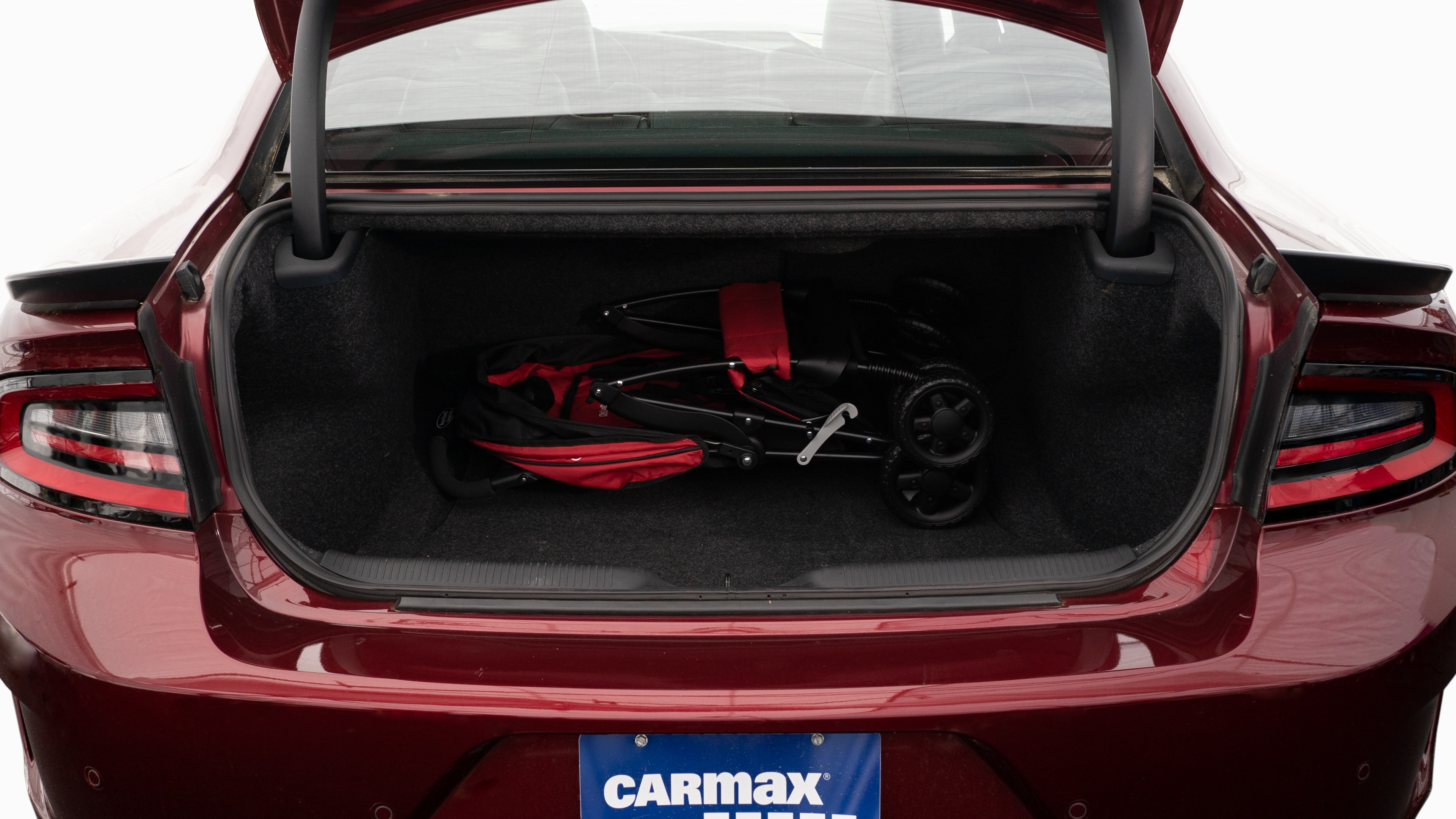 The trunk lid is open showing full view of the trunk. A baby stroller, four grocery carriers, a yoga mat, and a set of golf clubs are placed inside.