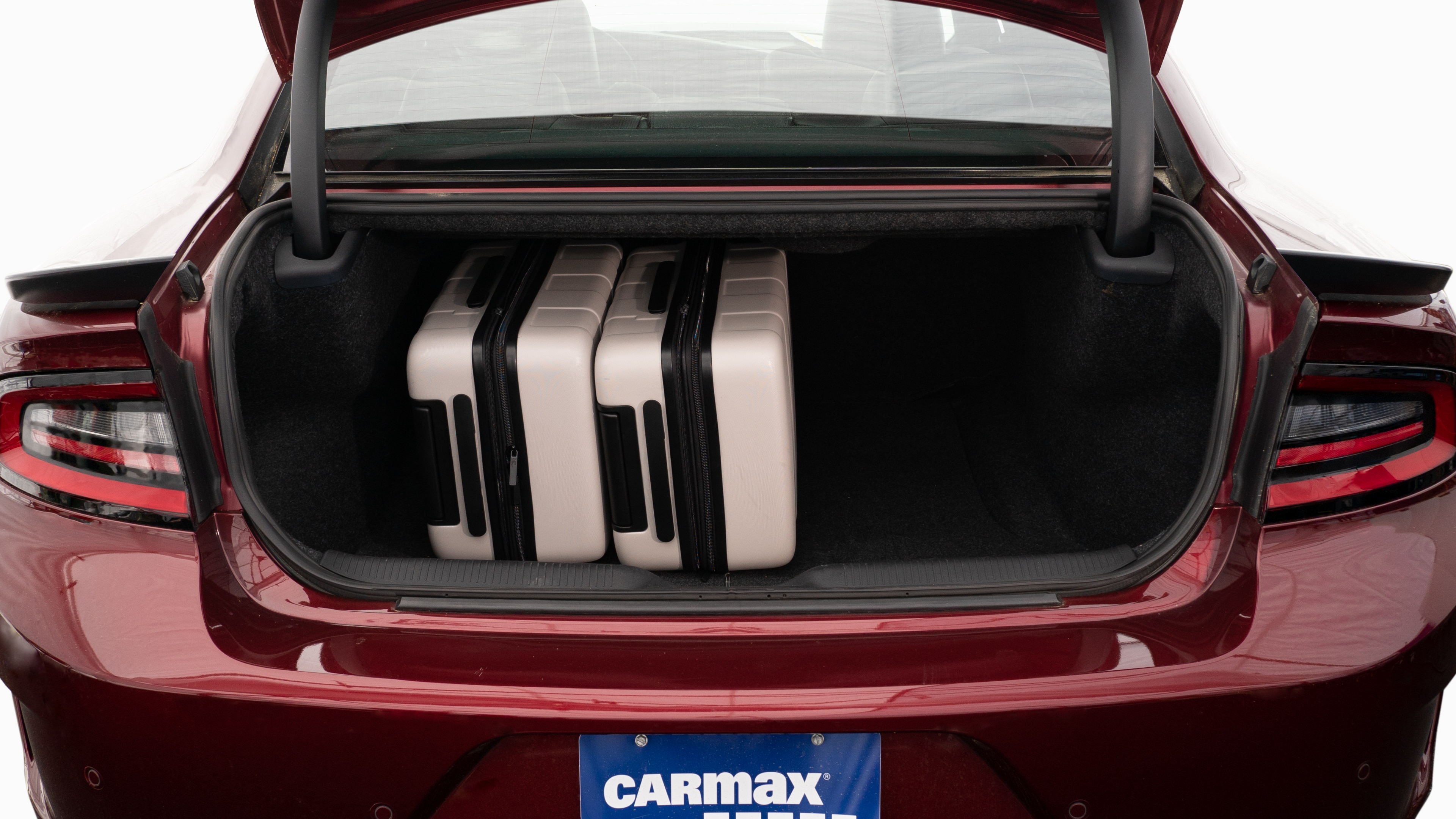 The trunk lid is open, showing full view of the trunk space. Two large and two small suitcases are placed inside.