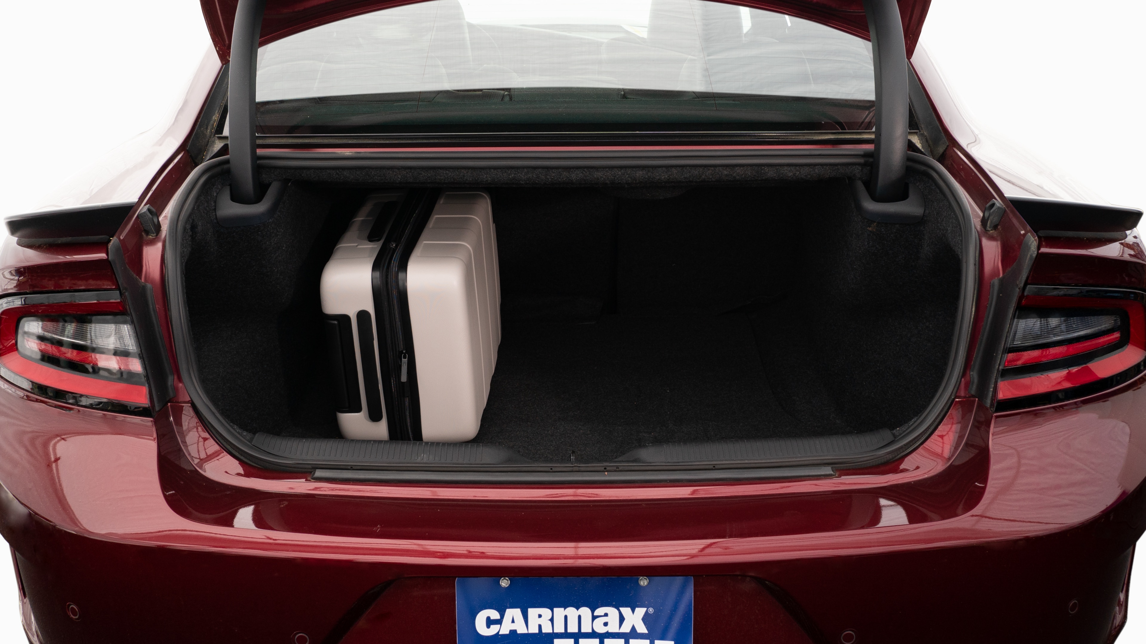 The trunk lid is open, showing full view of the trunk space. Two large and two small suitcases are placed inside.