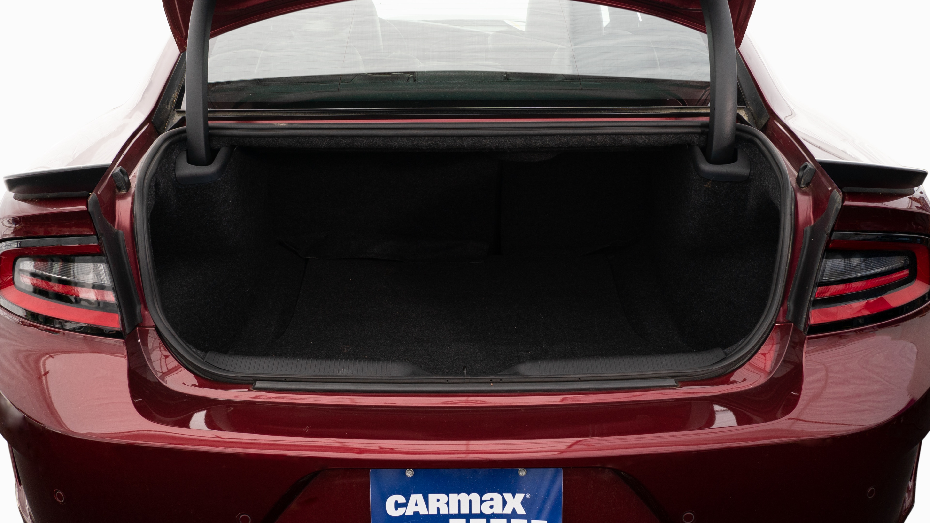 The trunk lid is open, showing full view of the trunk space. Two large and two small suitcases are placed inside.