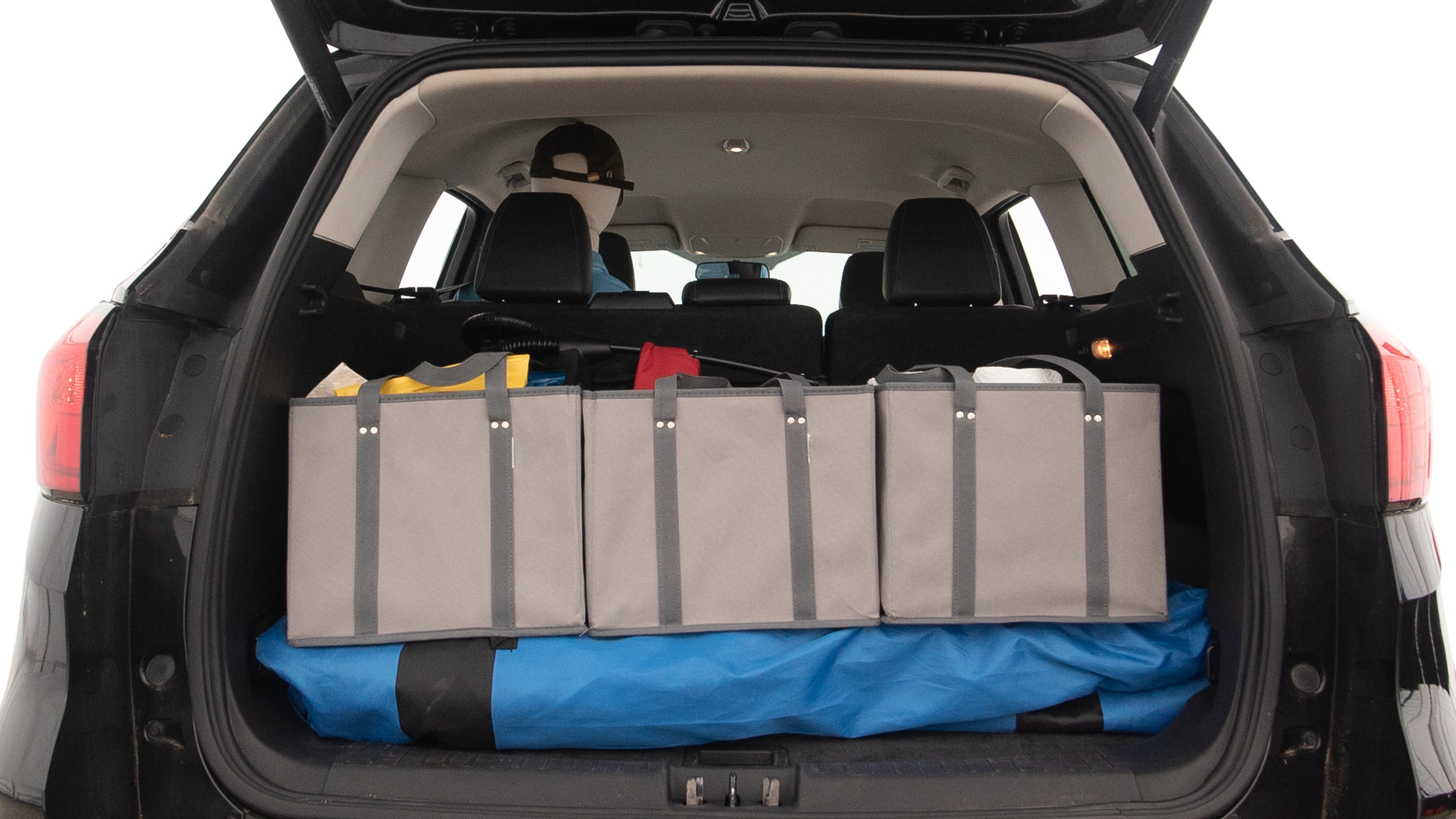 The trunk lid is open showing full view of the trunk. A baby stroller, three grocery carriers, two camping chairs in the carrying bag, and a set of golf clubs are placed inside.