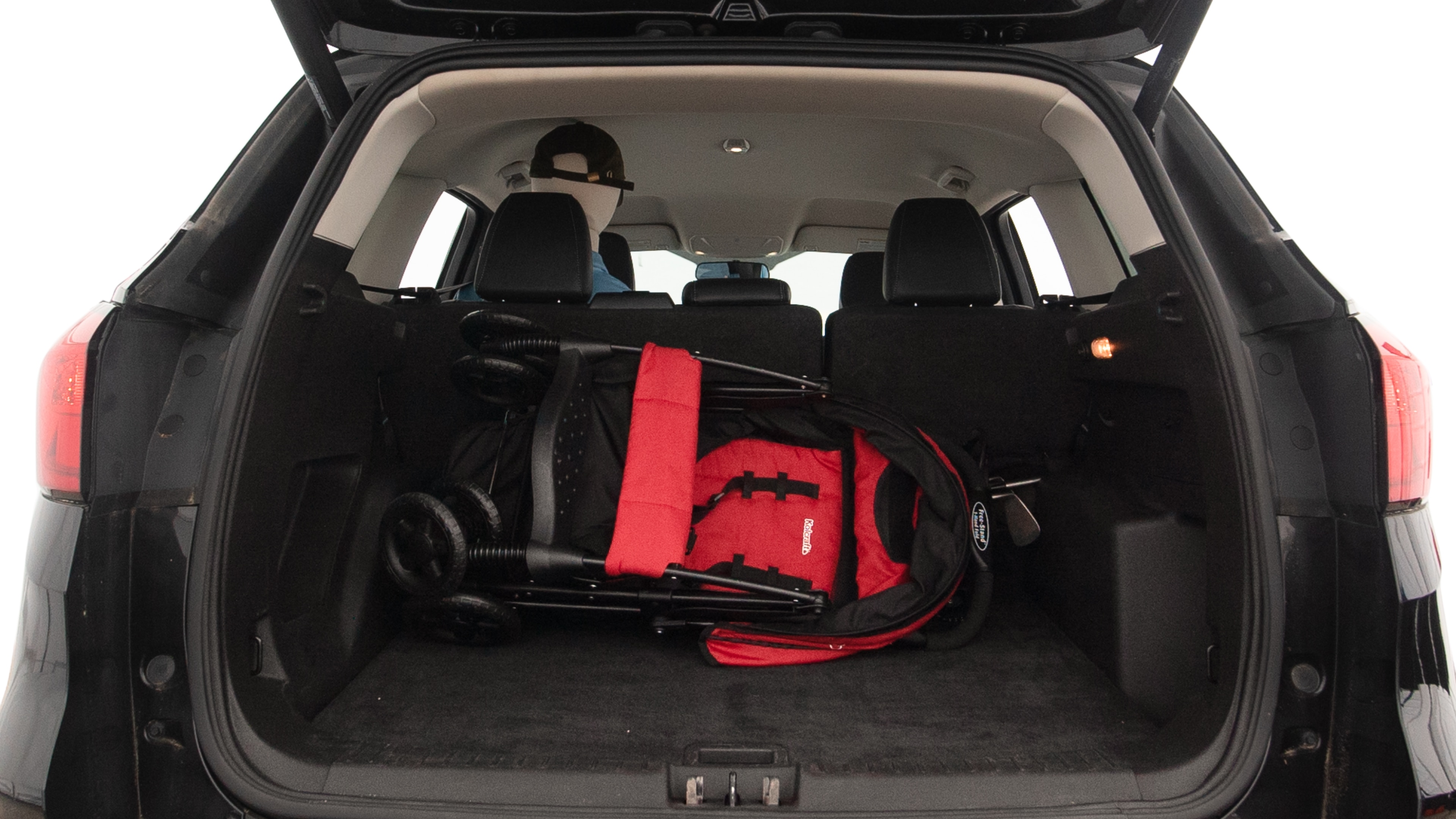 The trunk lid is open showing full view of the trunk. A baby stroller, three grocery carriers, two camping chairs in the carrying bag, and a set of golf clubs are placed inside.