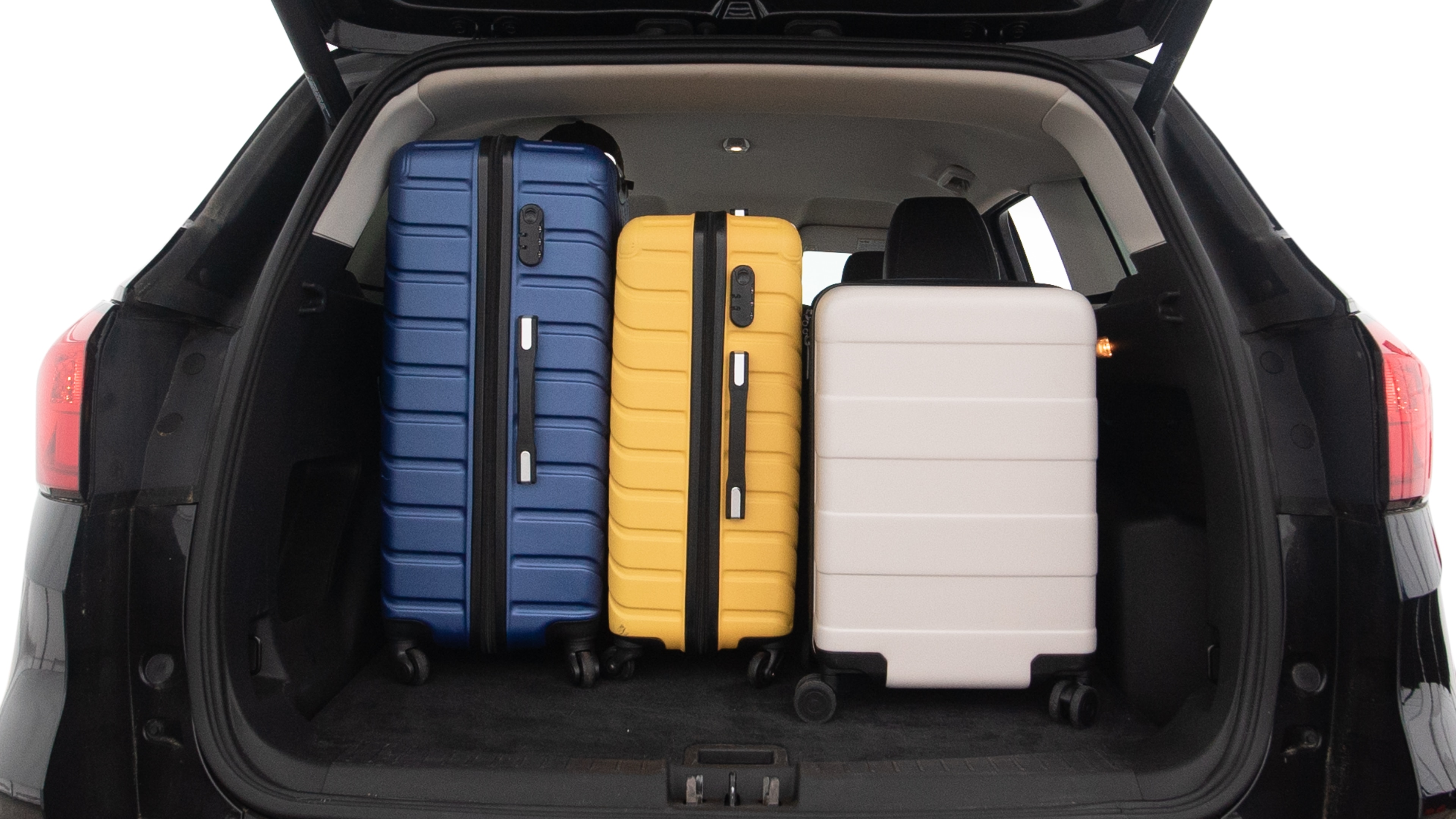 The trunk lid is open, showing full view of the trunk space. One large, two medium and two small suitcases are placed inside.