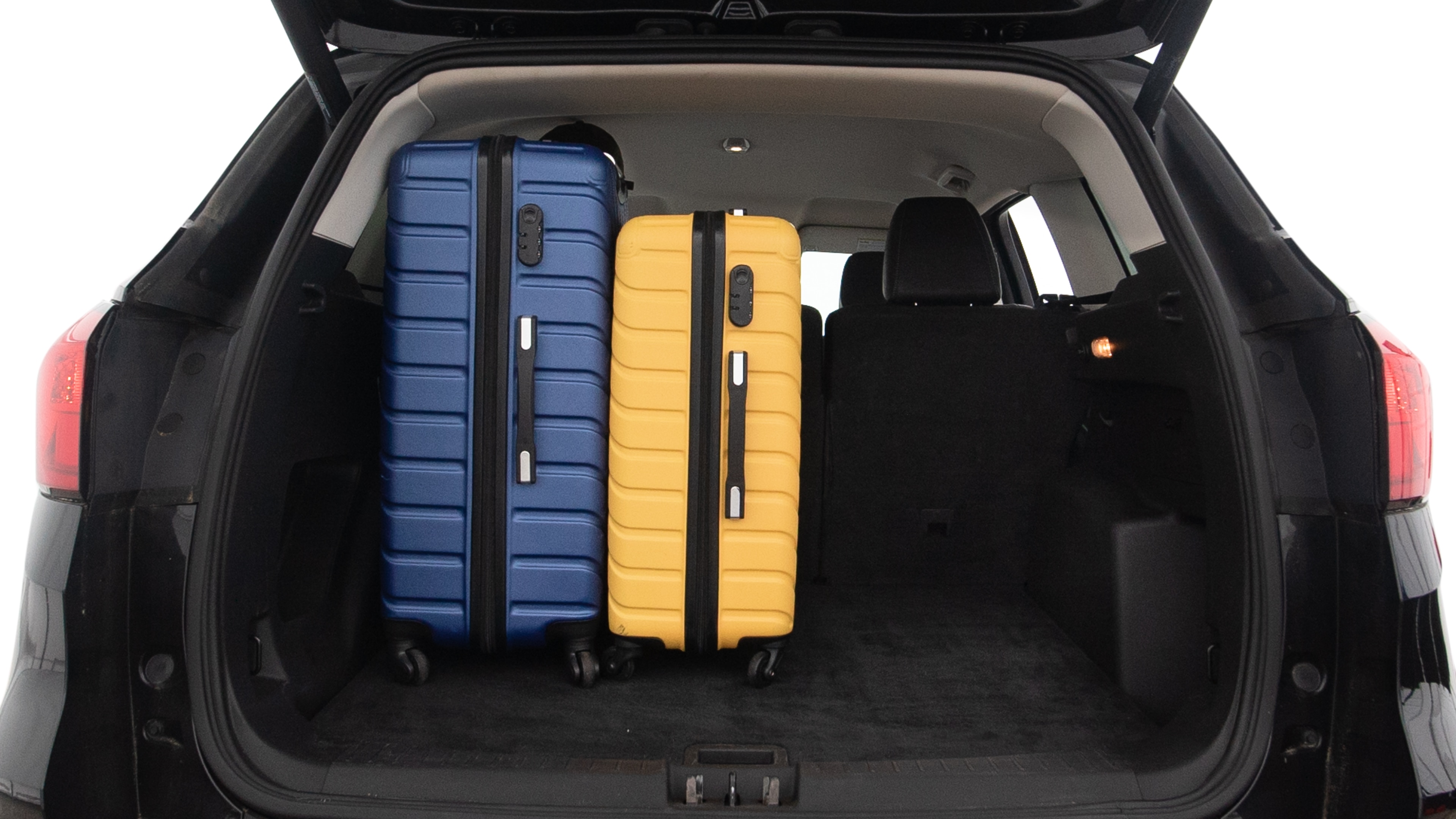 The trunk lid is open, showing full view of the trunk space. One large, two medium and two small suitcases are placed inside.