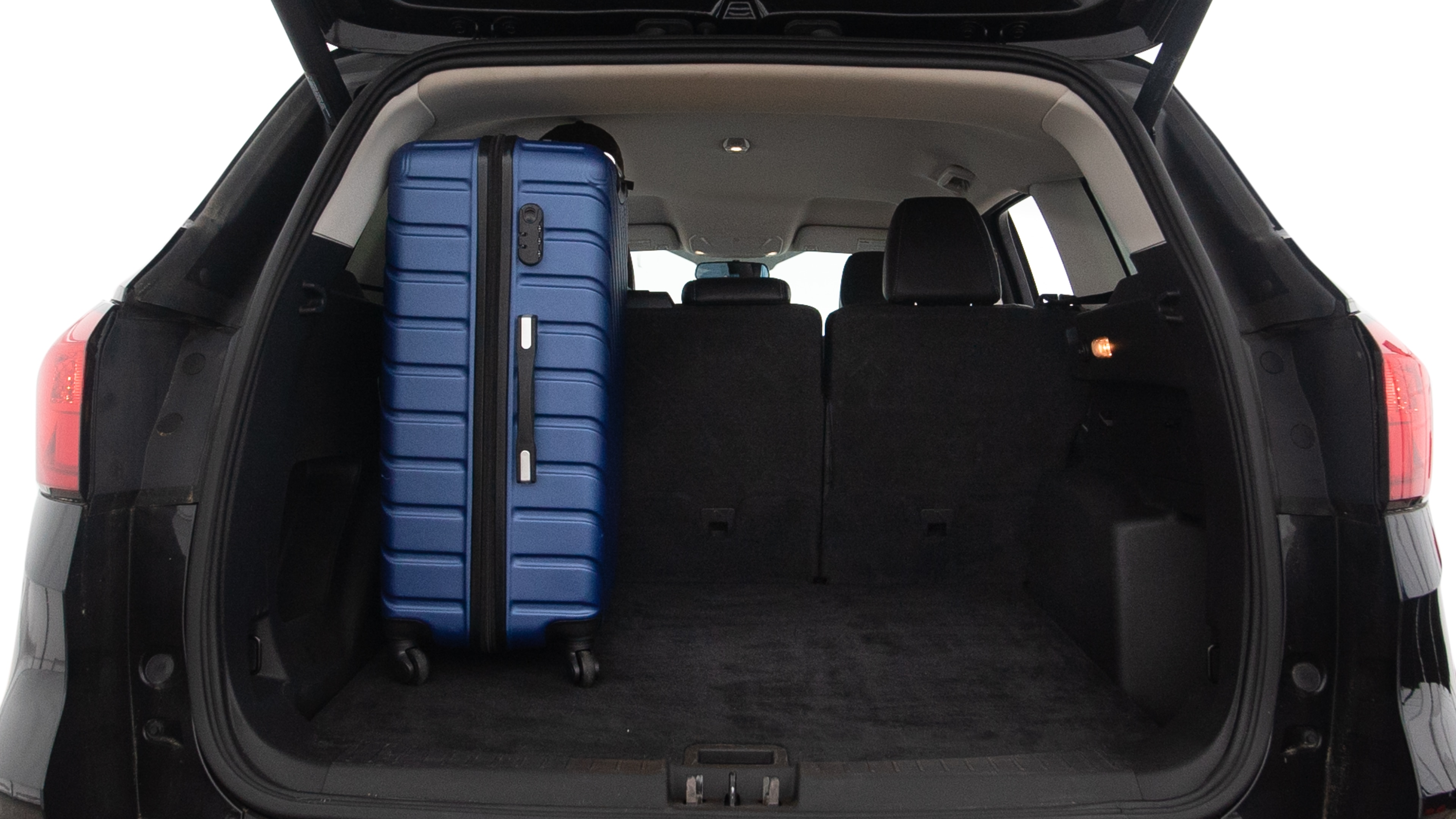 The trunk lid is open, showing full view of the trunk space. One large, two medium and two small suitcases are placed inside.
