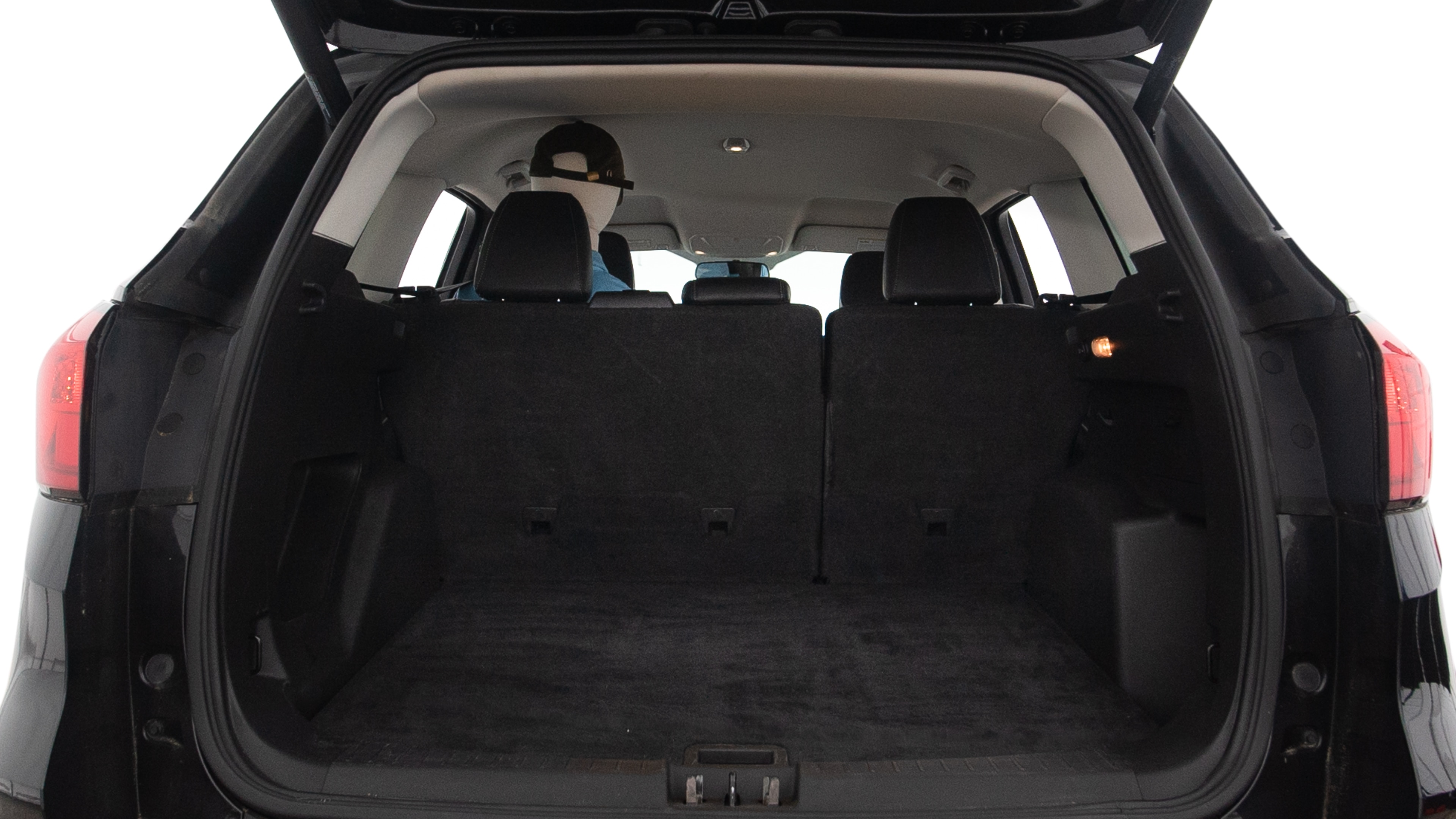 The trunk lid is open, showing full view of the trunk space. One large, two medium and two small suitcases are placed inside.