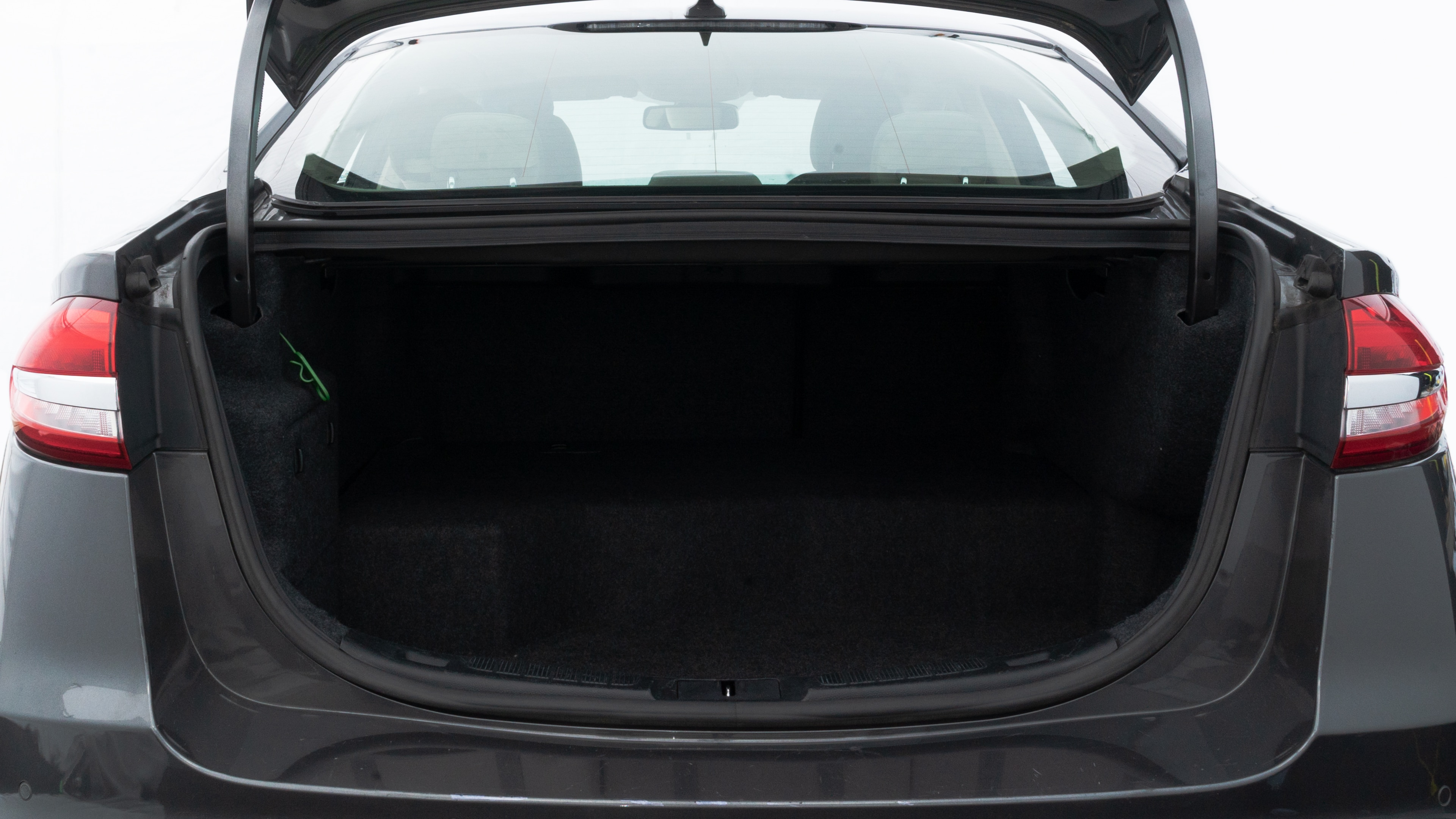 The trunk lid is open, showing full view of the trunk space. Two medium and two small suitcases are placed inside.