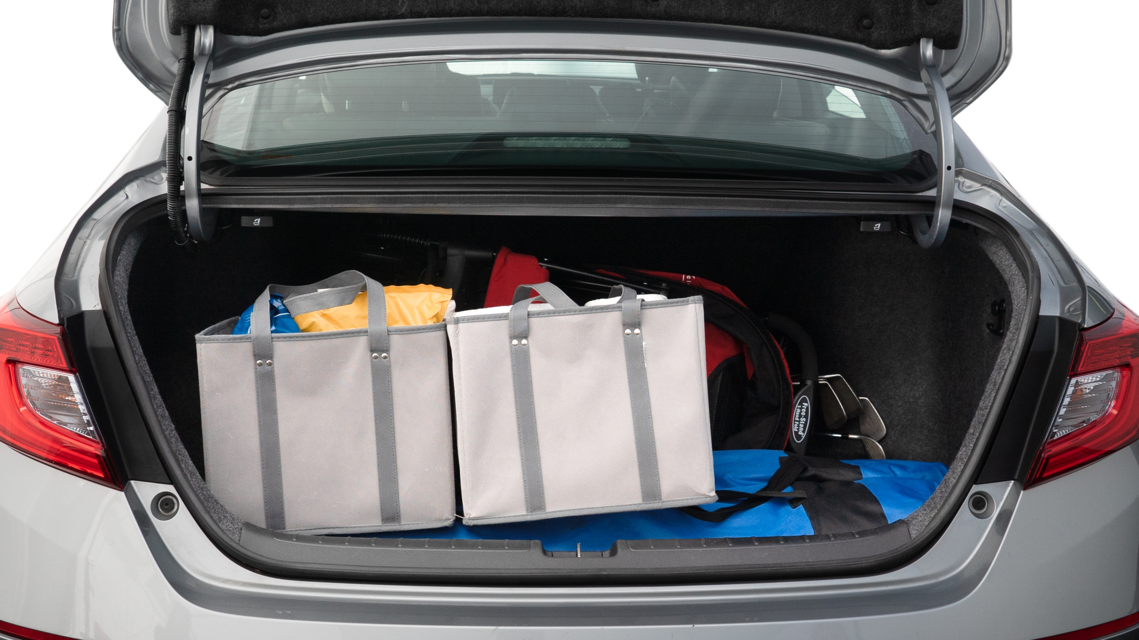 The trunk lid is open showing full view of the trunk. A baby stroller, three grocery carriers, two camping chairs in the carrying bag, and a set of golf clubs are placed inside.