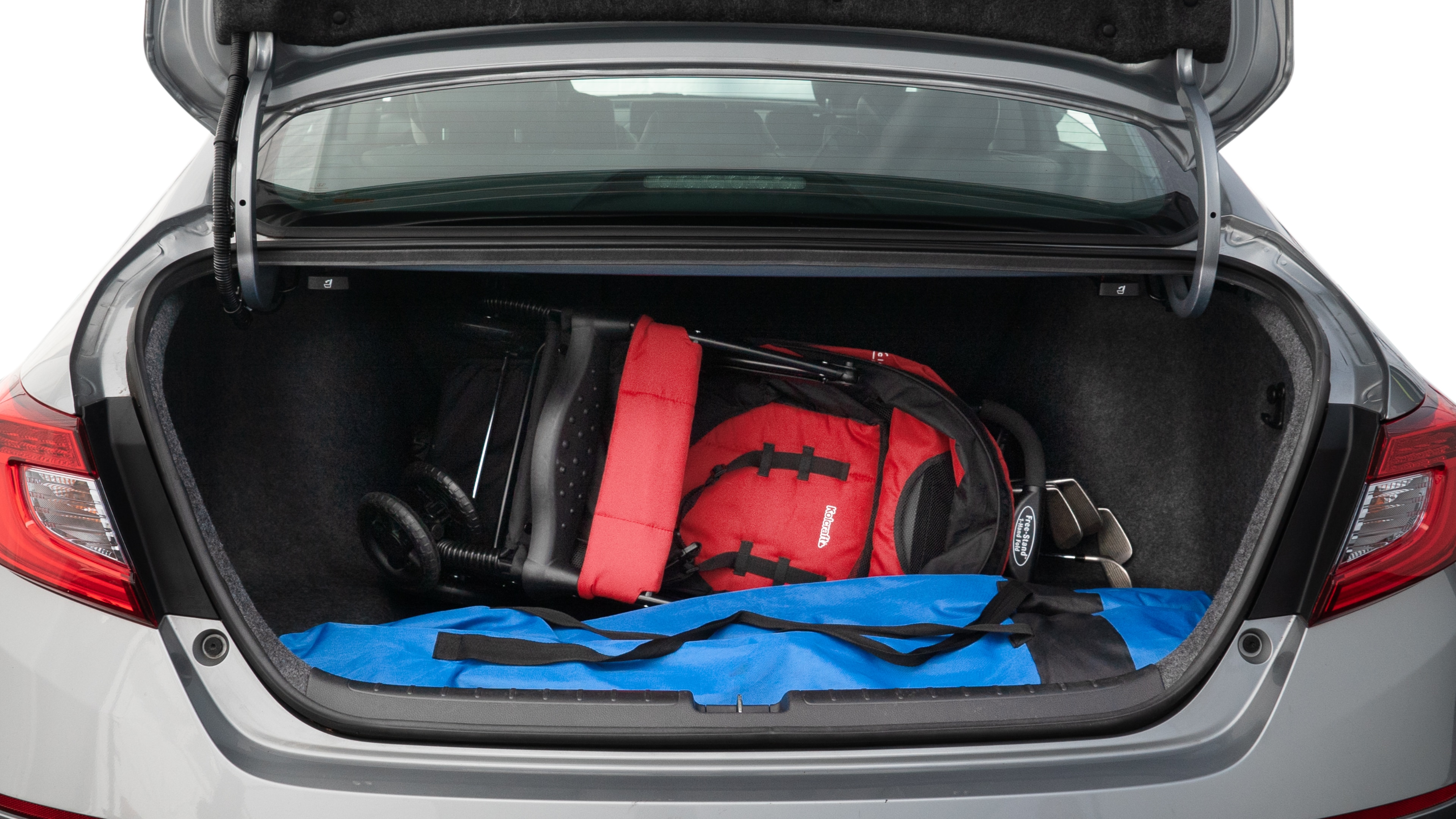 The trunk lid is open showing full view of the trunk. A baby stroller, three grocery carriers, two camping chairs in the carrying bag, and a set of golf clubs are placed inside.