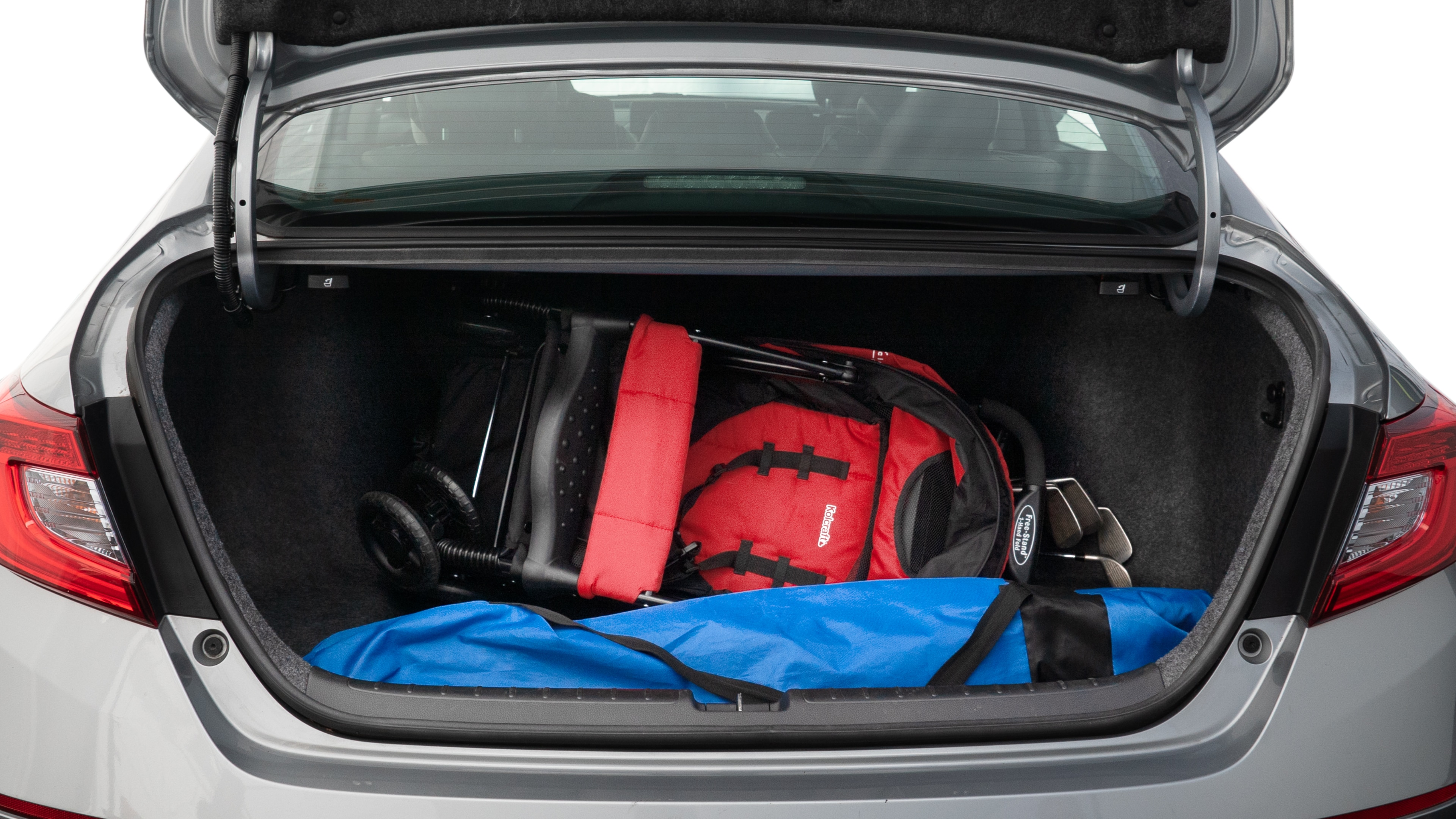 The trunk lid is open showing full view of the trunk. A baby stroller, three grocery carriers, two camping chairs in the carrying bag, and a set of golf clubs are placed inside.