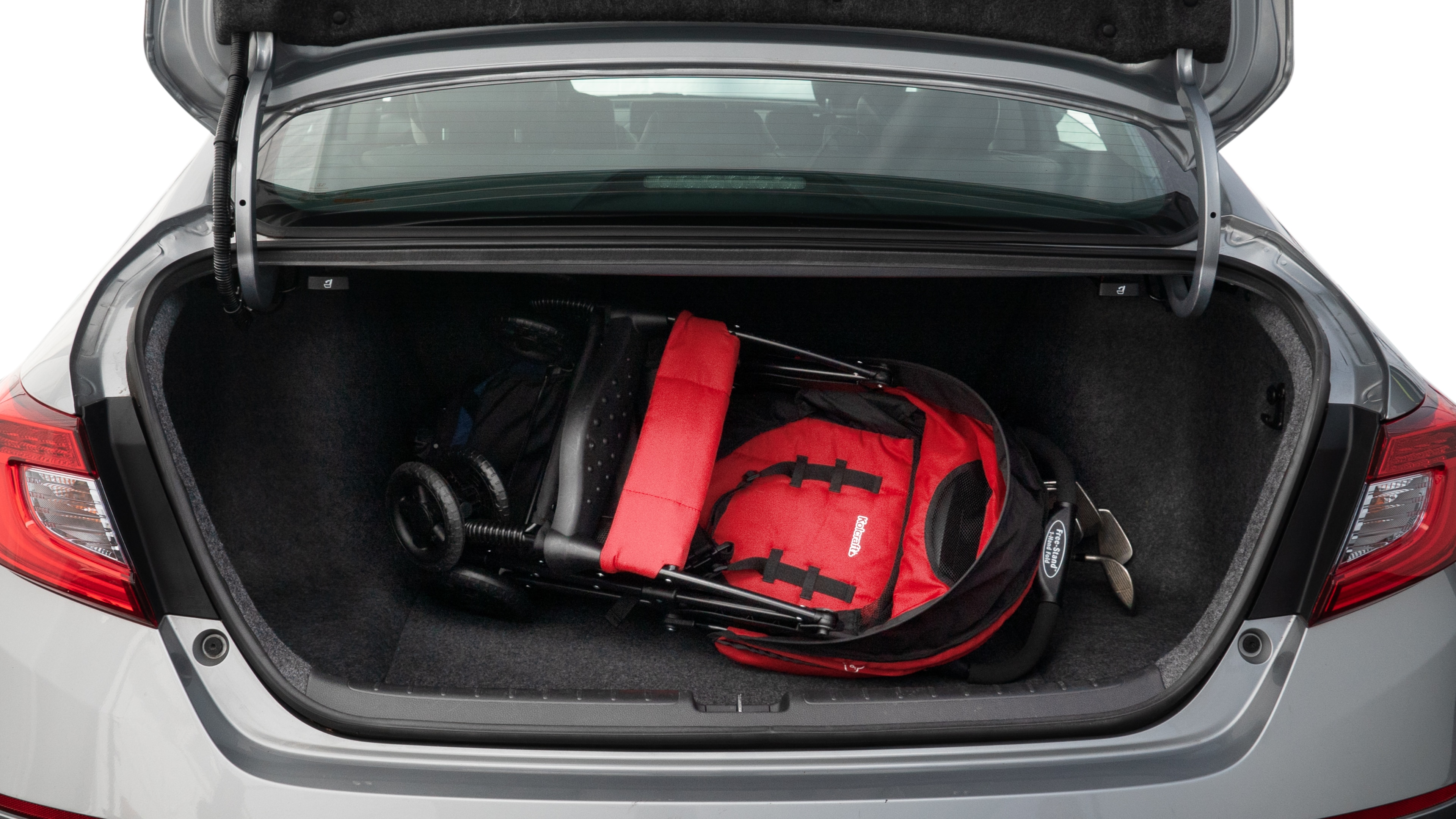 The trunk lid is open showing full view of the trunk. A baby stroller, three grocery carriers, two camping chairs in the carrying bag, and a set of golf clubs are placed inside.