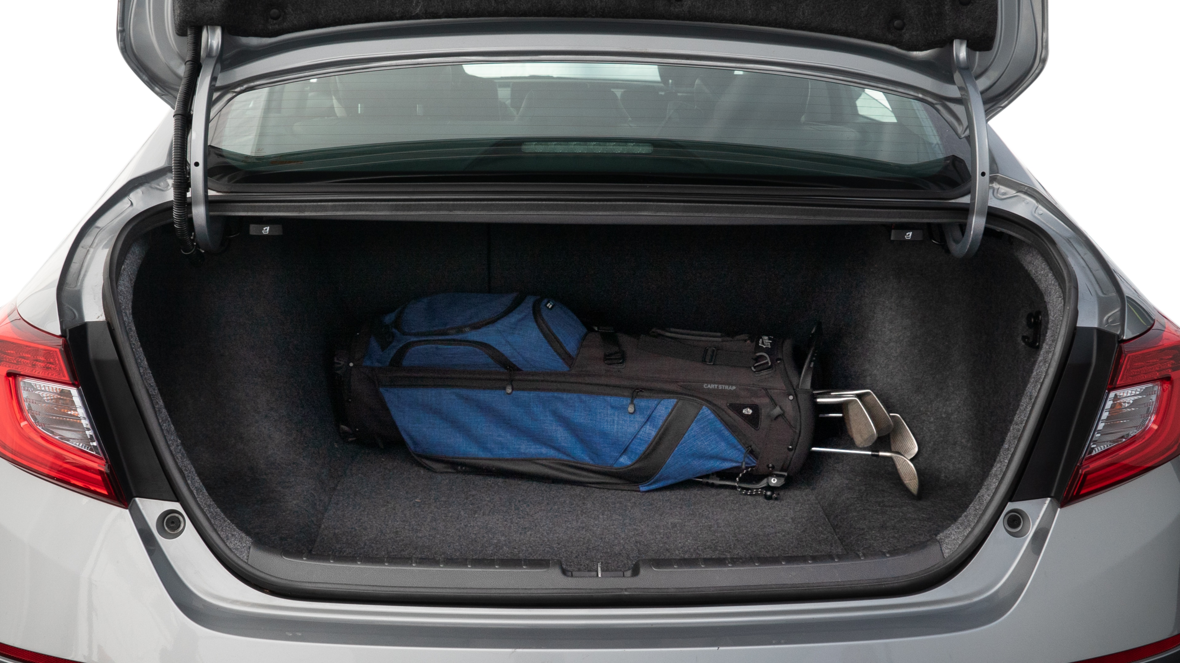 The trunk lid is open showing full view of the trunk. A baby stroller, three grocery carriers, two camping chairs in the carrying bag, and a set of golf clubs are placed inside.