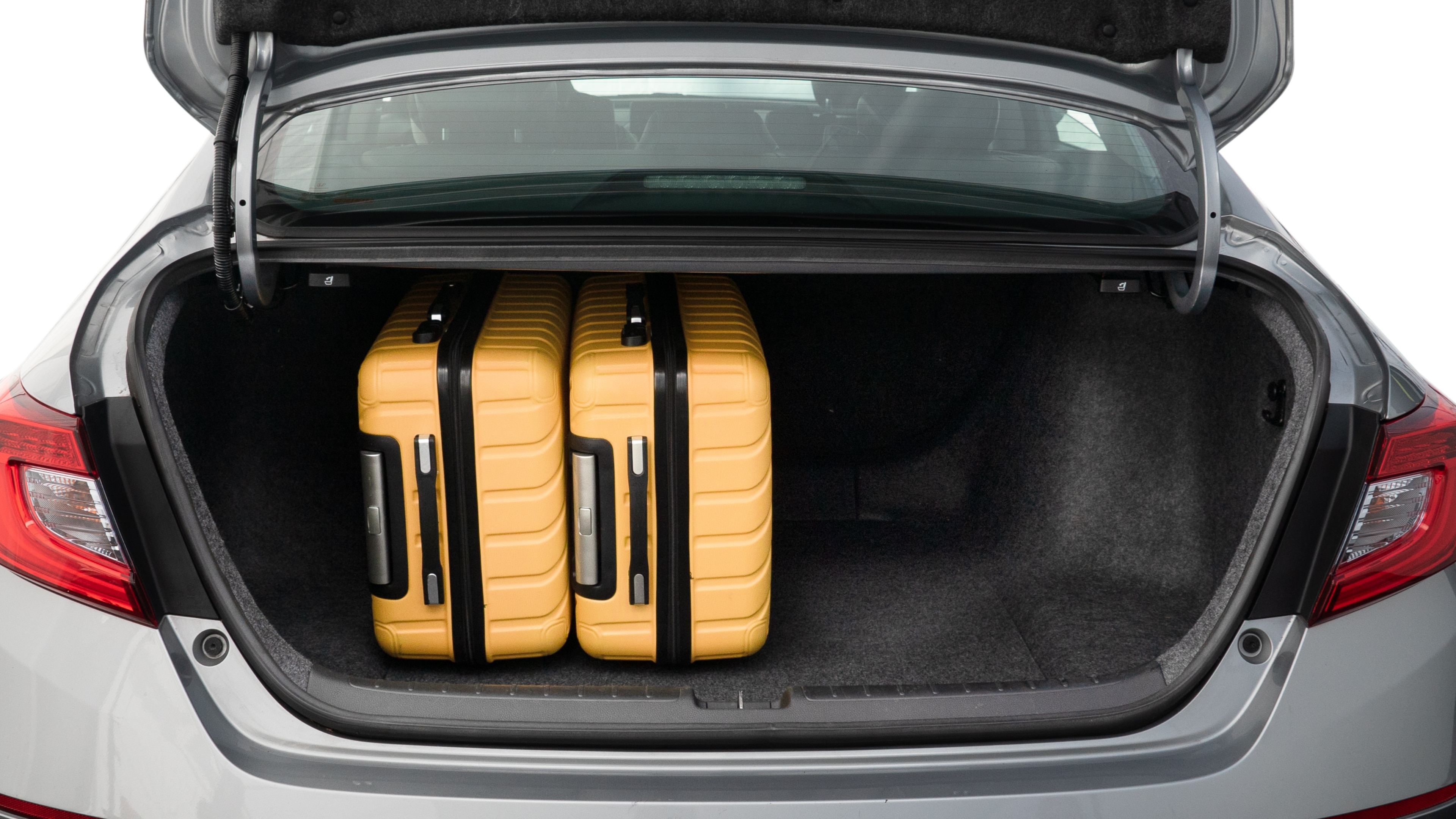 The trunk lid is open, showing full view of the trunk space. One large, two medium, and two small suitcases are placed inside.