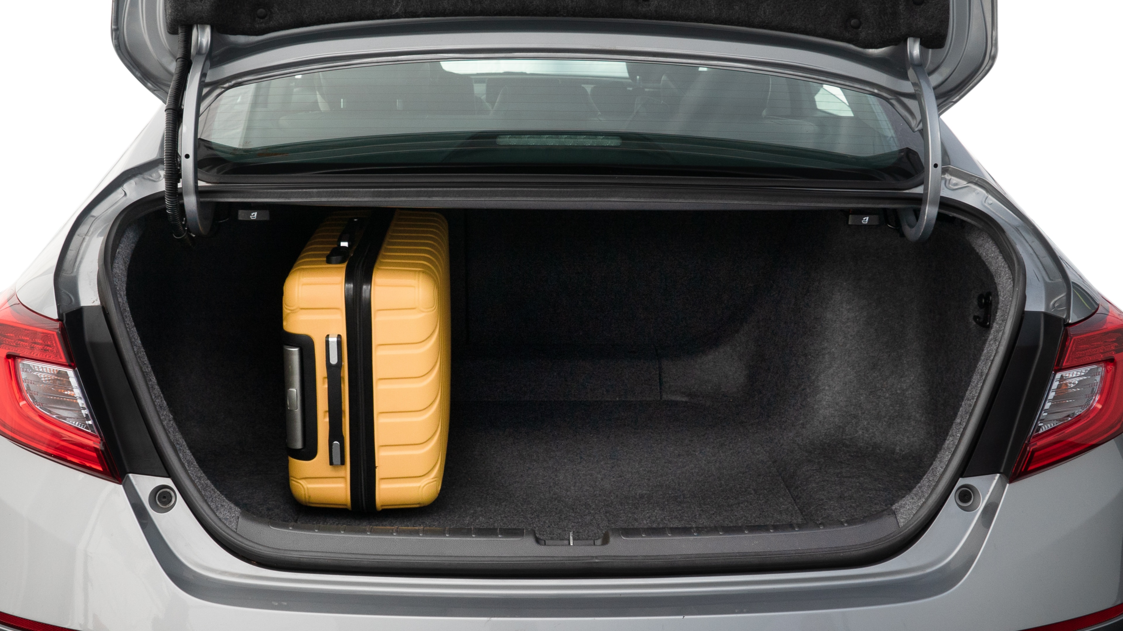 The trunk lid is open, showing full view of the trunk space. One large, two medium, and two small suitcases are placed inside.