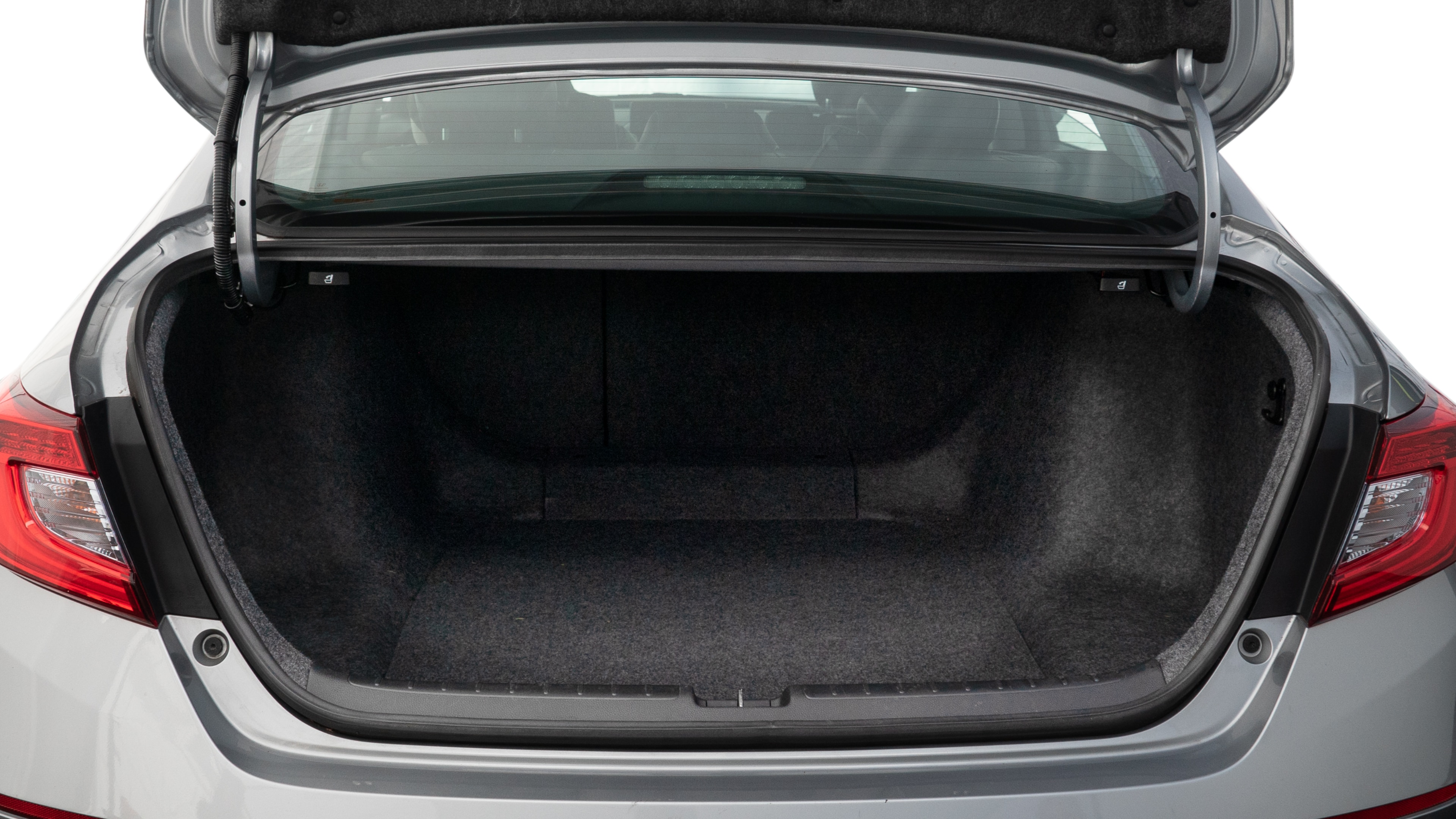 The trunk lid is open, showing full view of the trunk space. One large, two medium, and two small suitcases are placed inside.