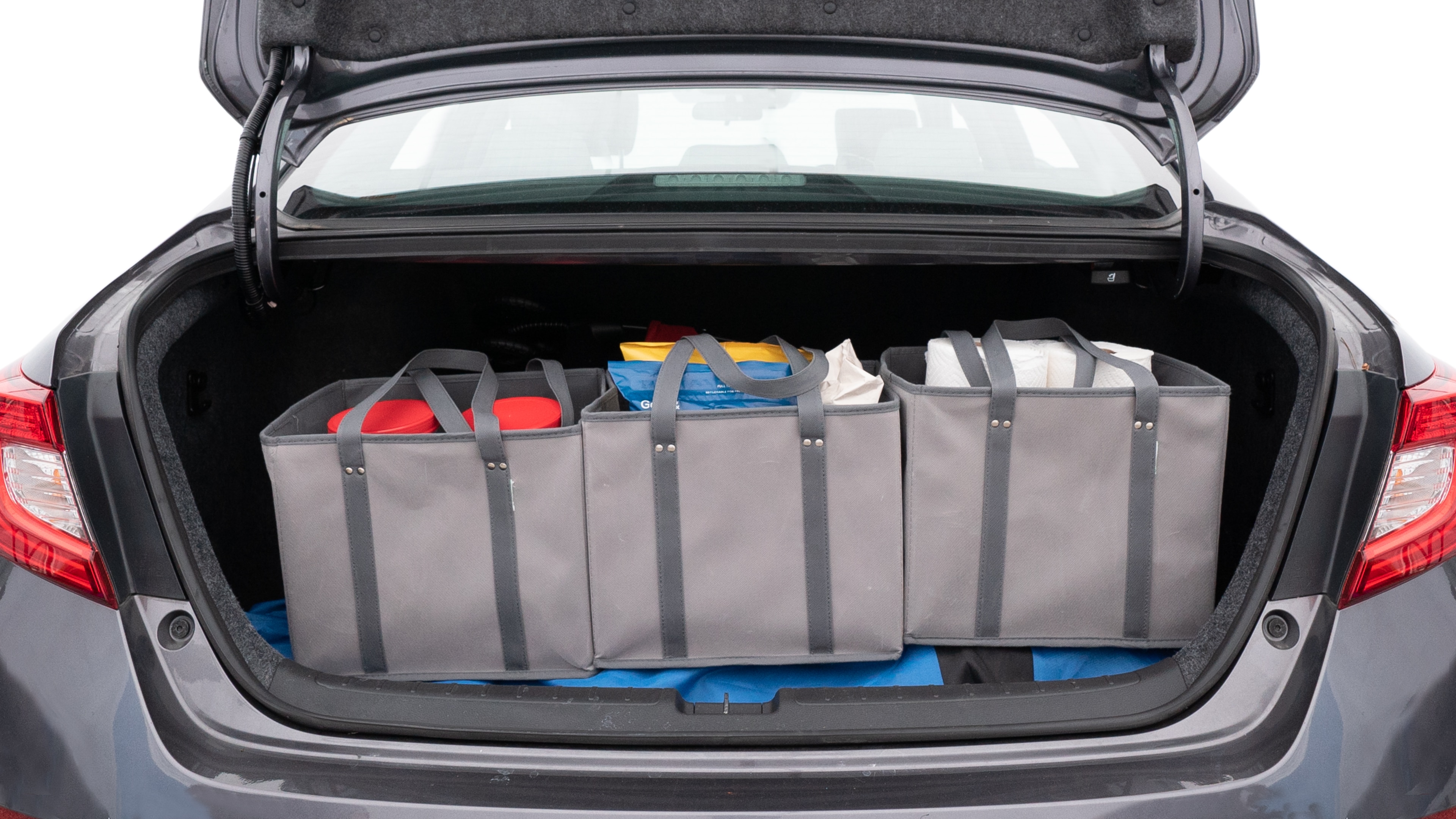 The trunk lid is open showing full view of the trunk. A baby stroller, three grocery carriers, two camping chairs in the carrying bag, and a set of golf clubs are placed inside.