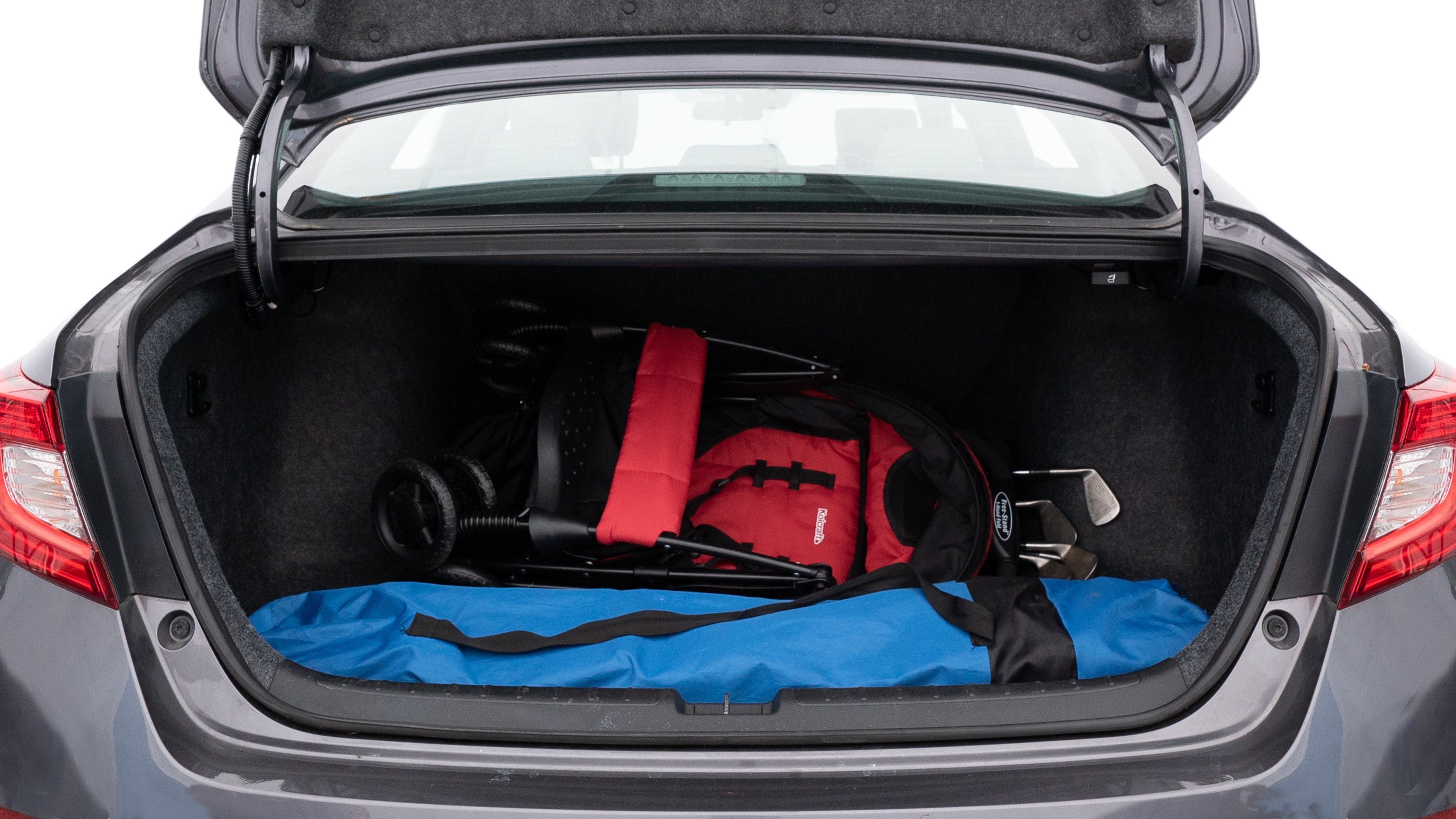 The trunk lid is open showing full view of the trunk. A baby stroller, three grocery carriers, two camping chairs in the carrying bag, and a set of golf clubs are placed inside.