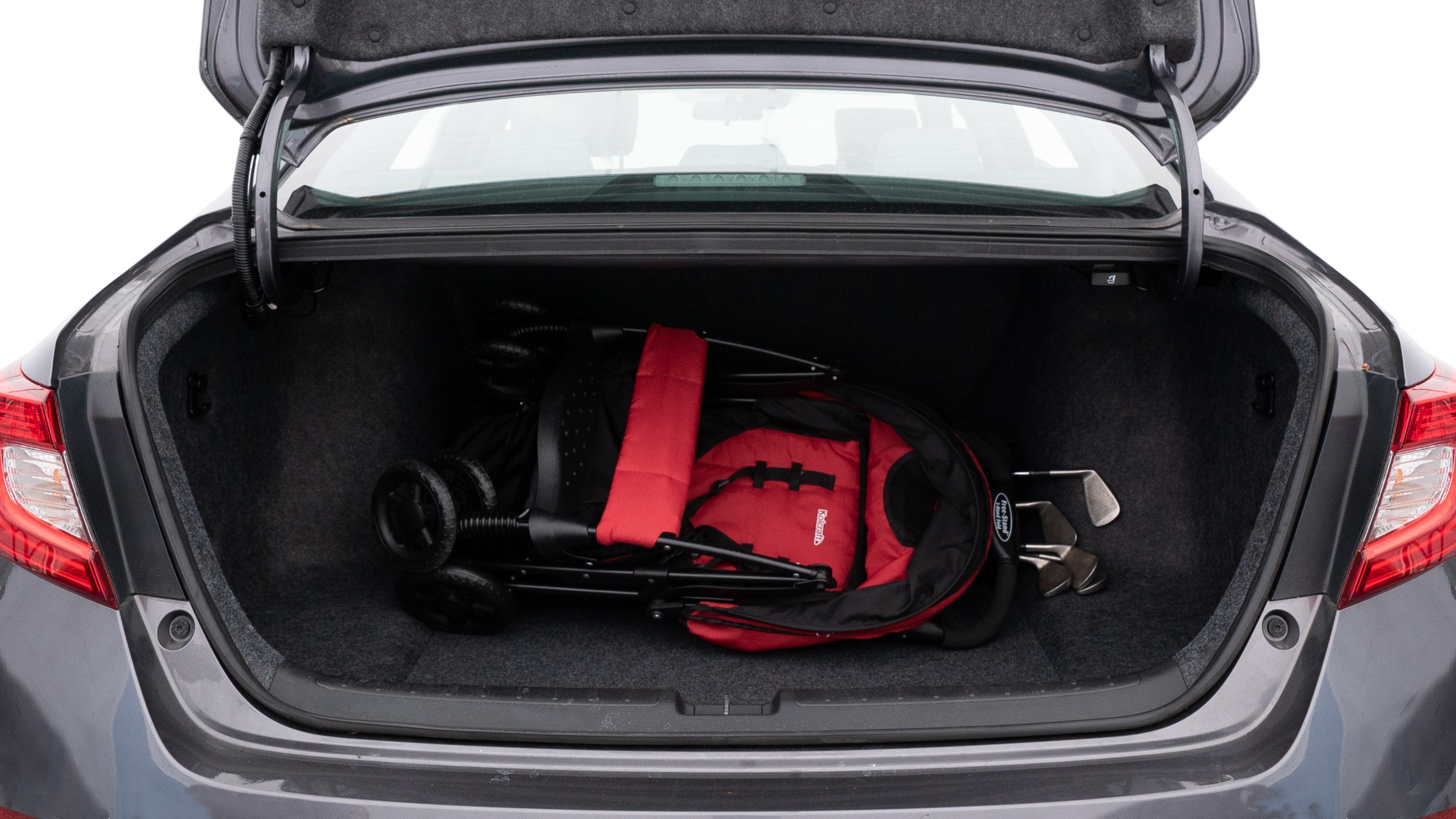 The trunk lid is open showing full view of the trunk. A baby stroller, three grocery carriers, two camping chairs in the carrying bag, and a set of golf clubs are placed inside.