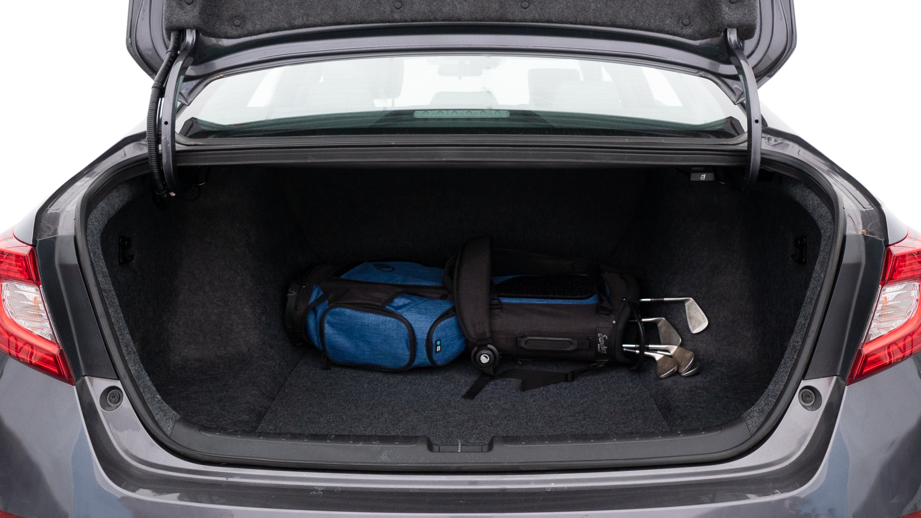 The trunk lid is open showing full view of the trunk. A baby stroller, three grocery carriers, two camping chairs in the carrying bag, and a set of golf clubs are placed inside.