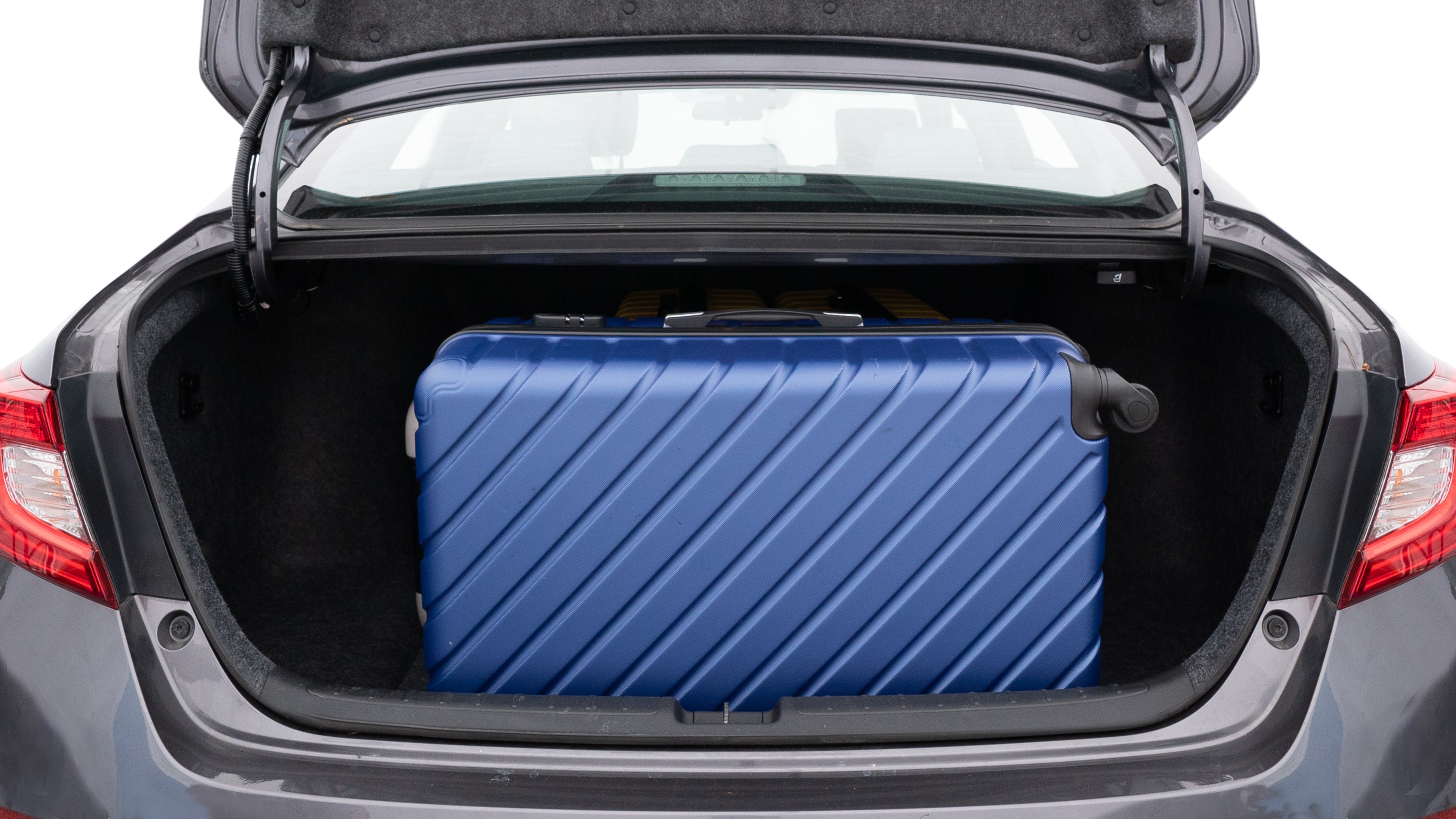 The trunk lid is open, showing full view of the trunk space. One large, two medium, and one small suitcases are placed inside.